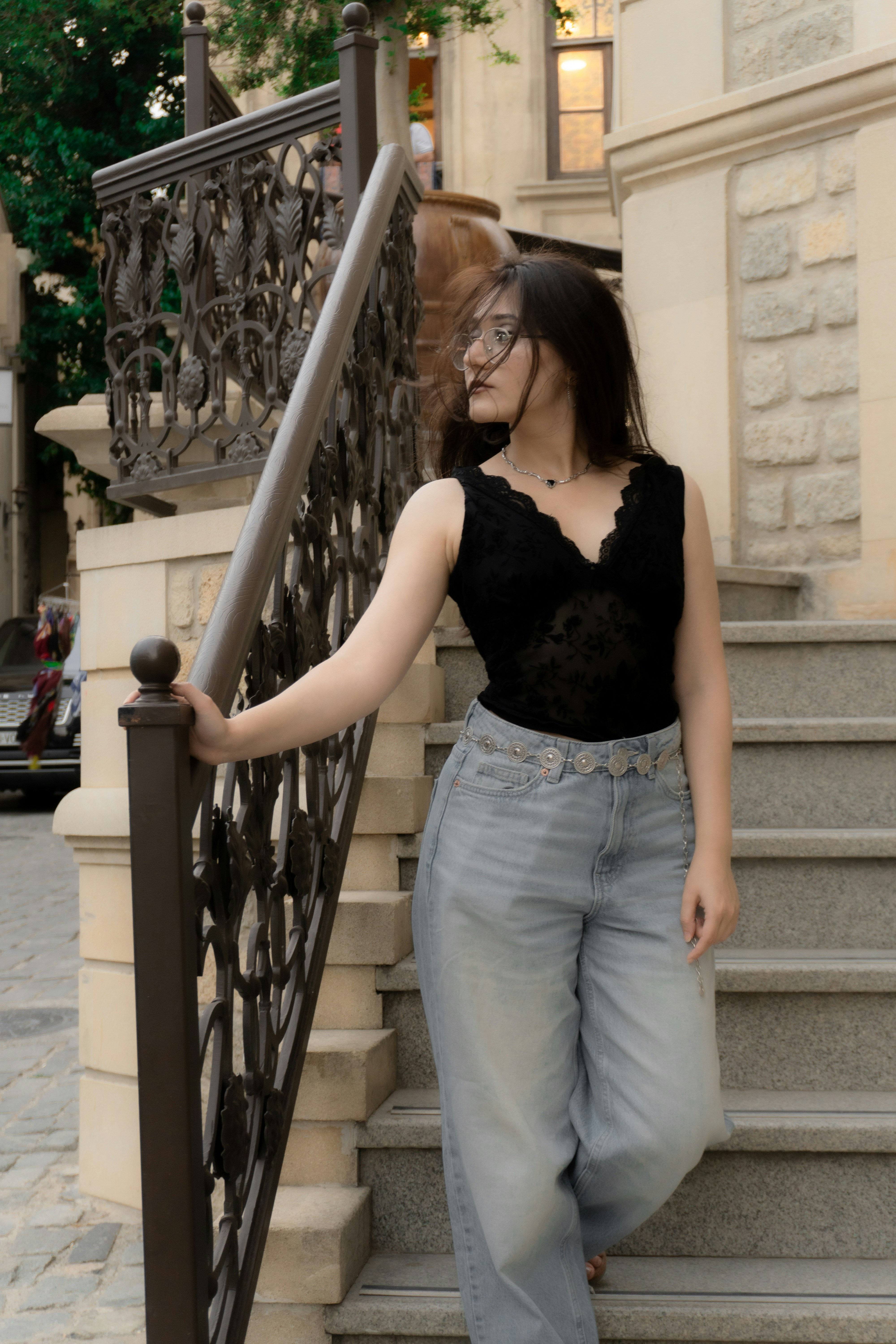 A woman in a black lace top and jeans on stone stairs