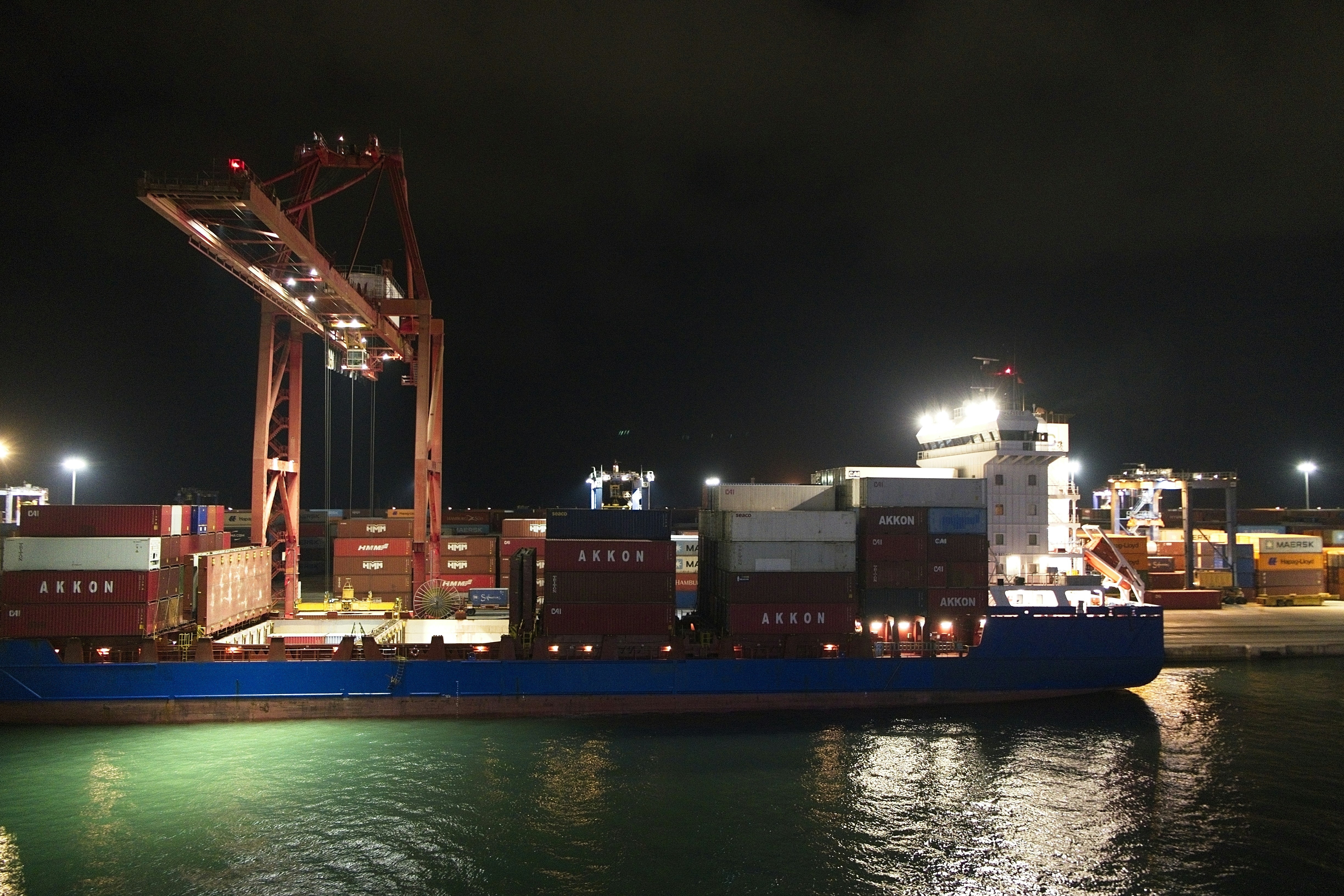 A container ship being loaded by a large crane at a night port