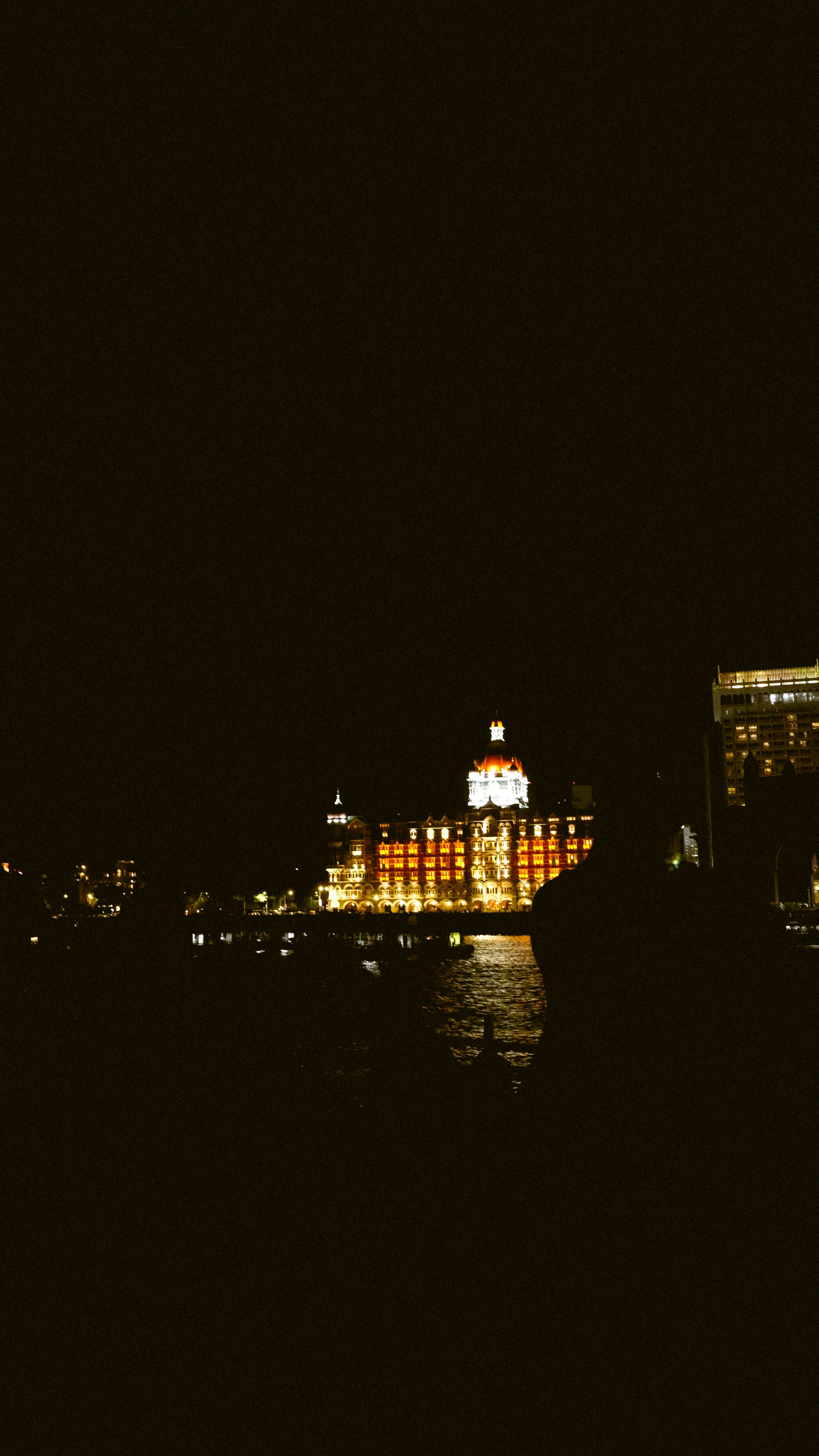 The Taj Mahal Palace hotel illuminated at night across the water in Mumbai