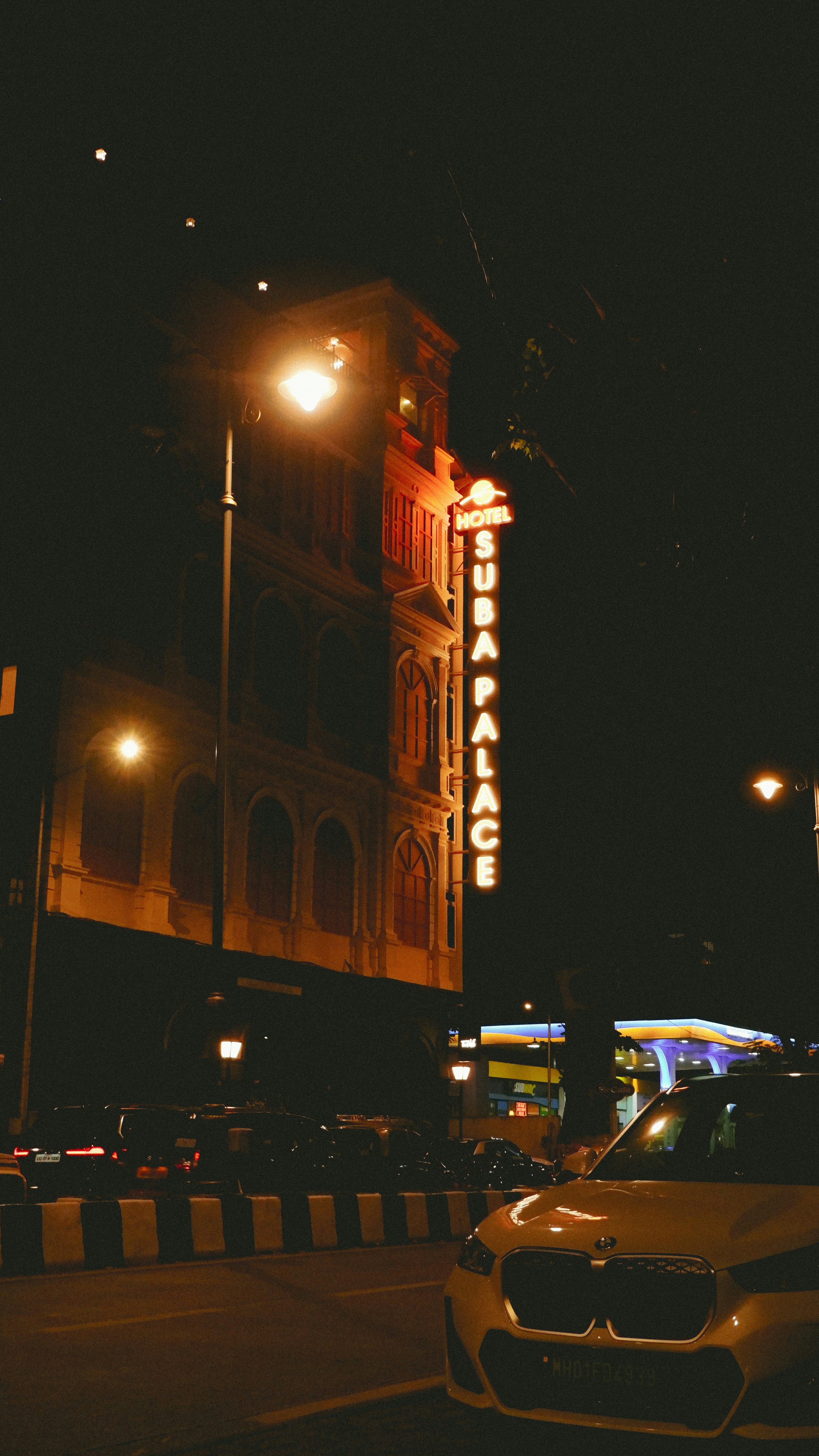 A neon sign reading Hotel Suba Palace on a building at night