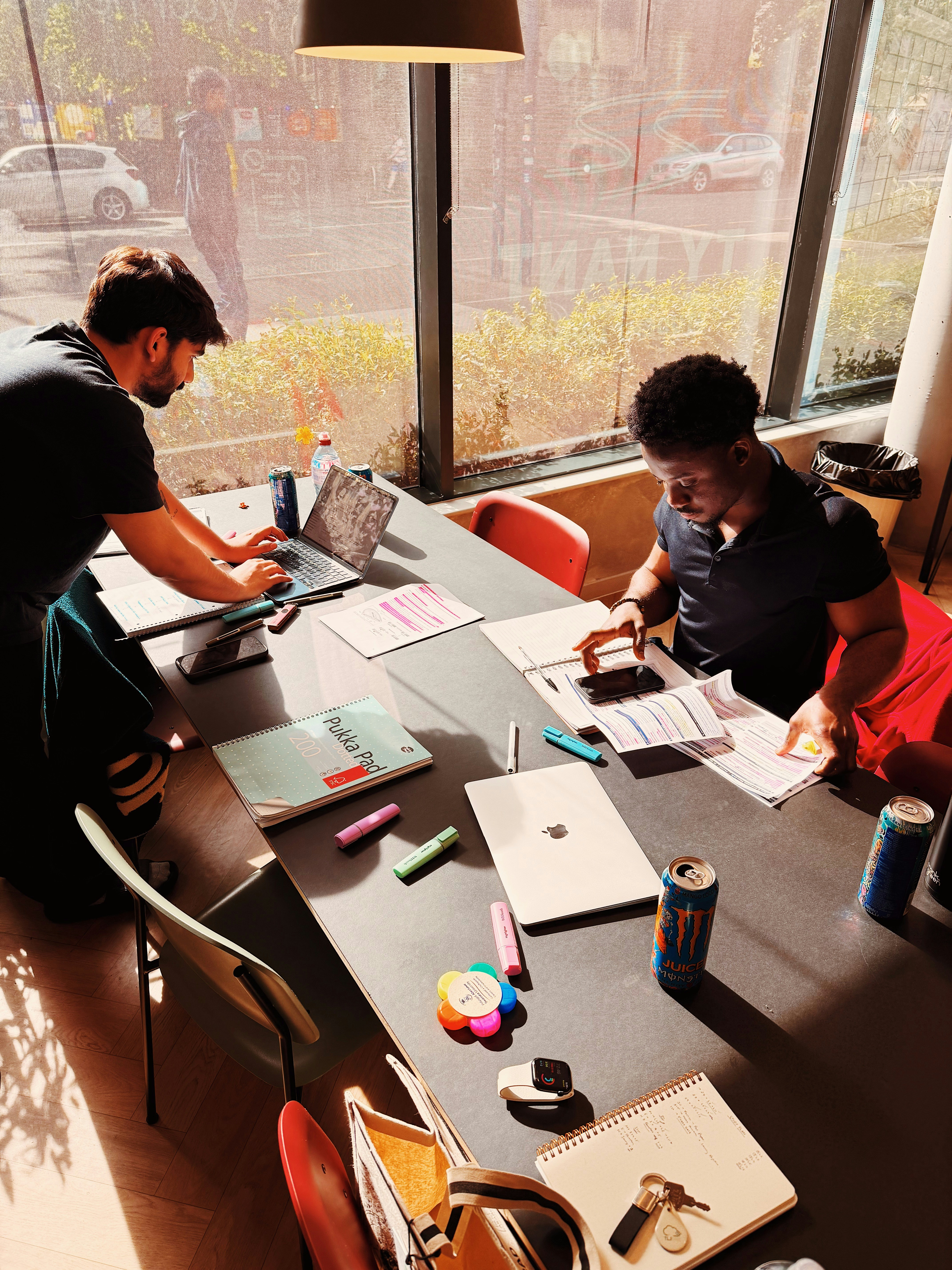 Two people working on laptops in a sunlit workspace