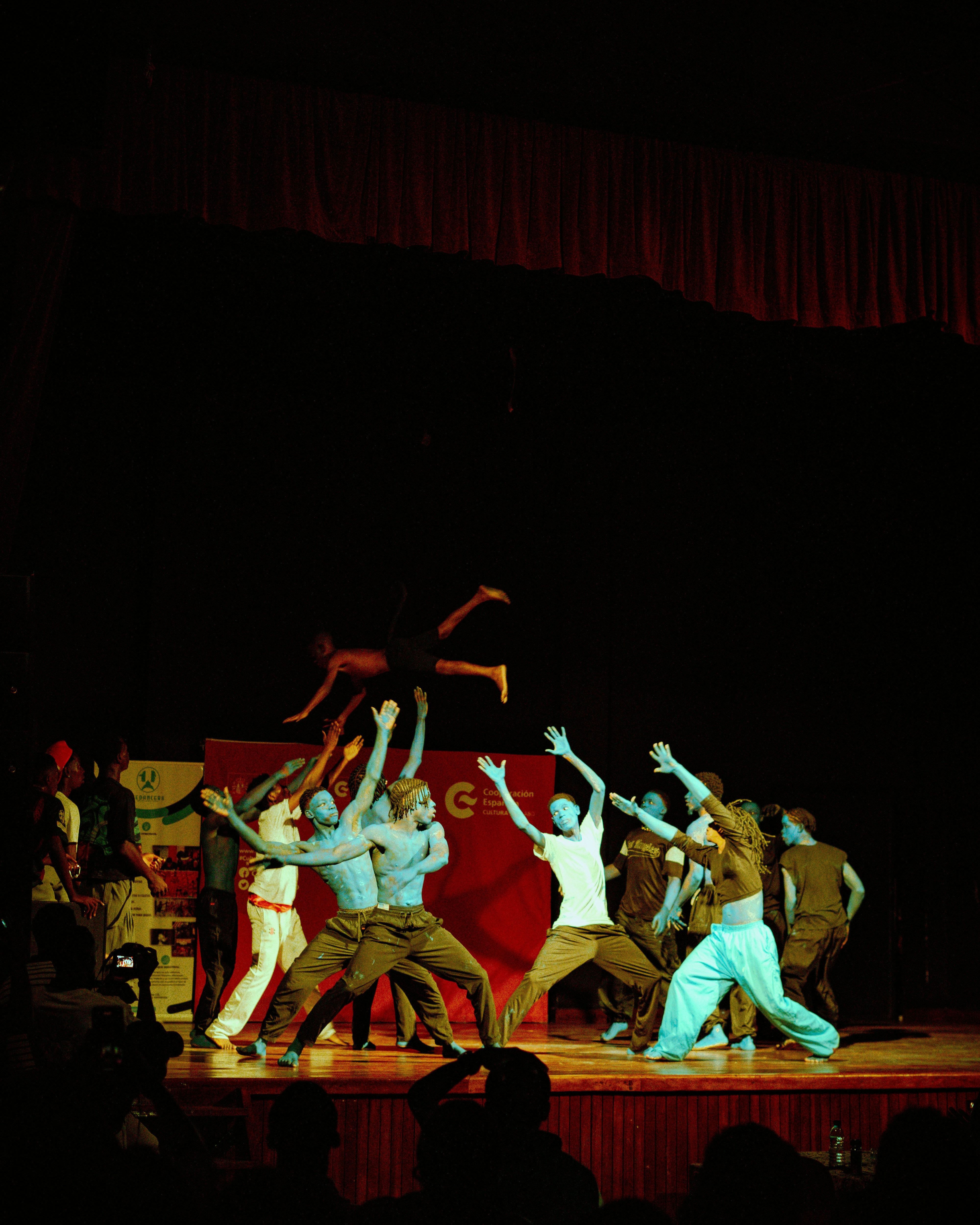 A group of dancers performing on a stage with one person lifted mid-air
