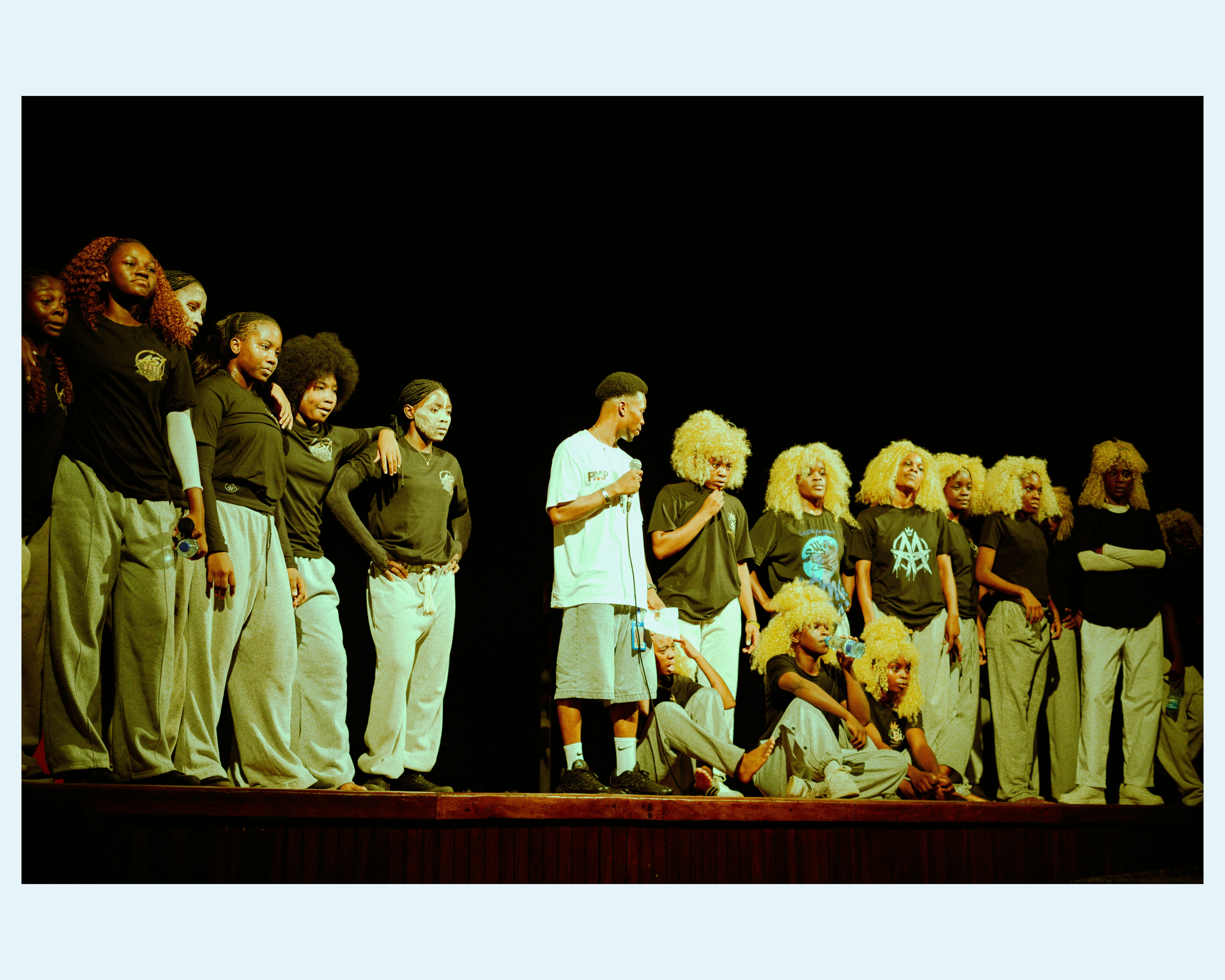 A group of people in black shirts and grey pants on a stage
