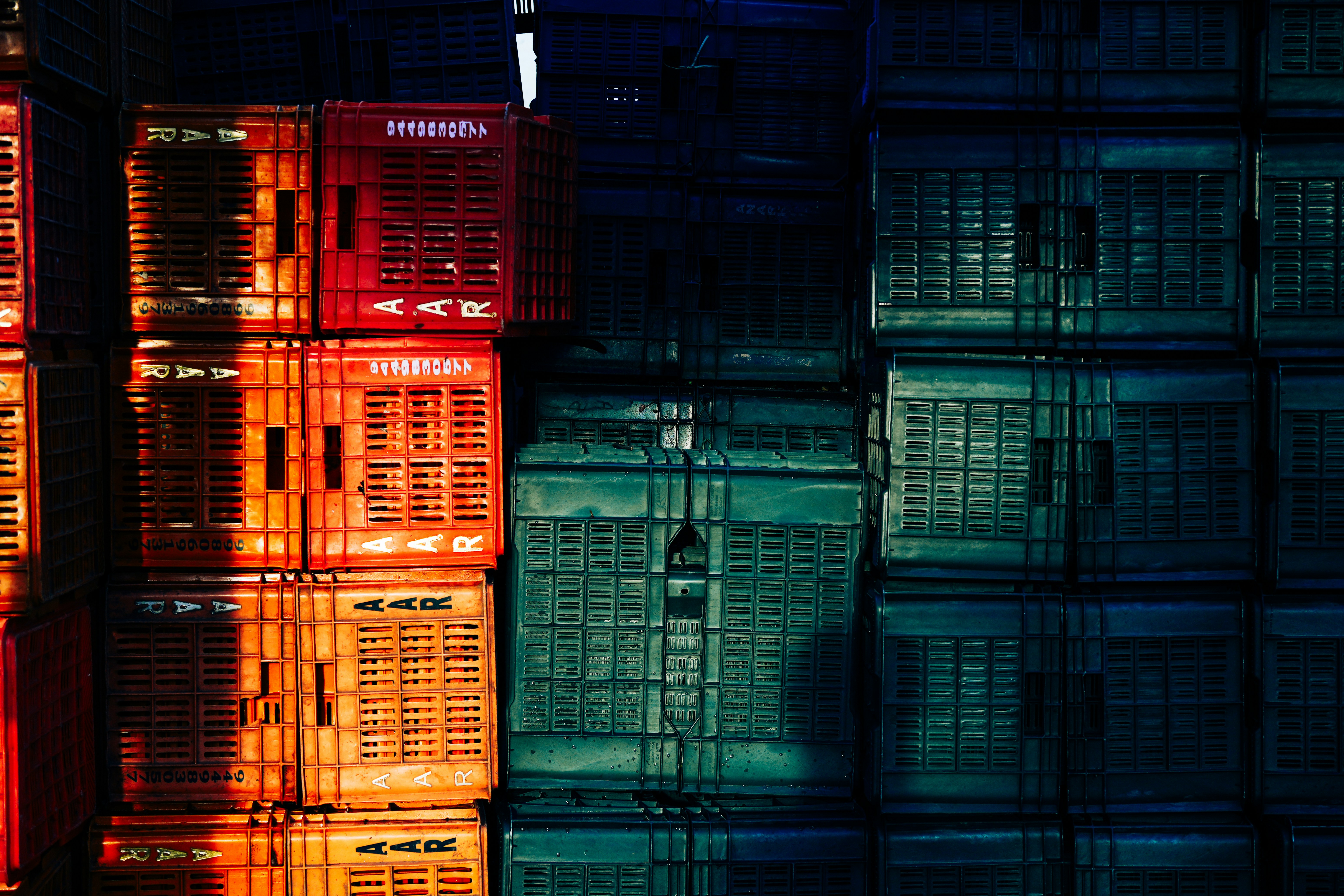 Stacked red and green plastic crates in bright sunlight and deep shadow