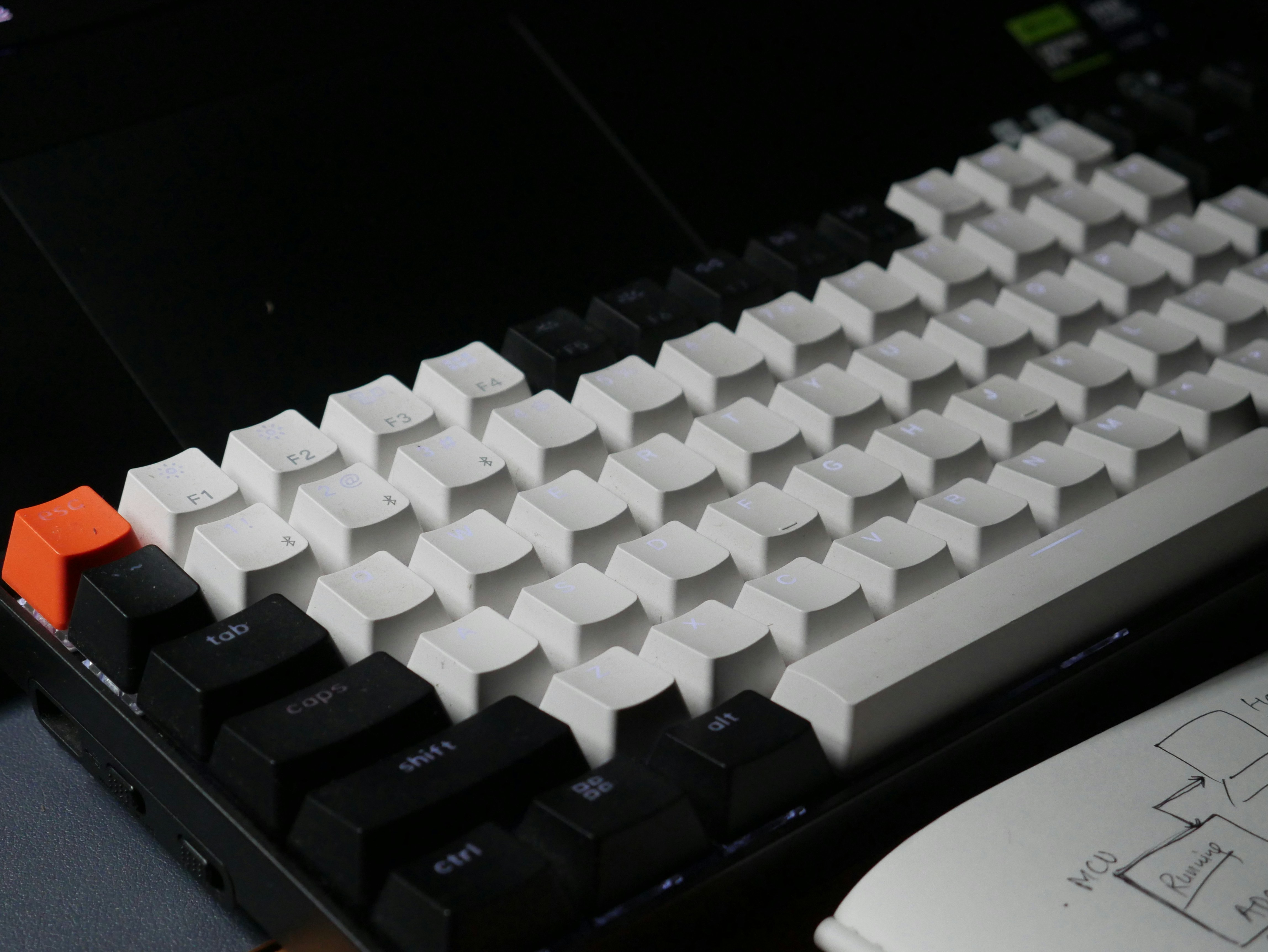 A mechanical keyboard with white keys, black modifiers, and an orange escape key