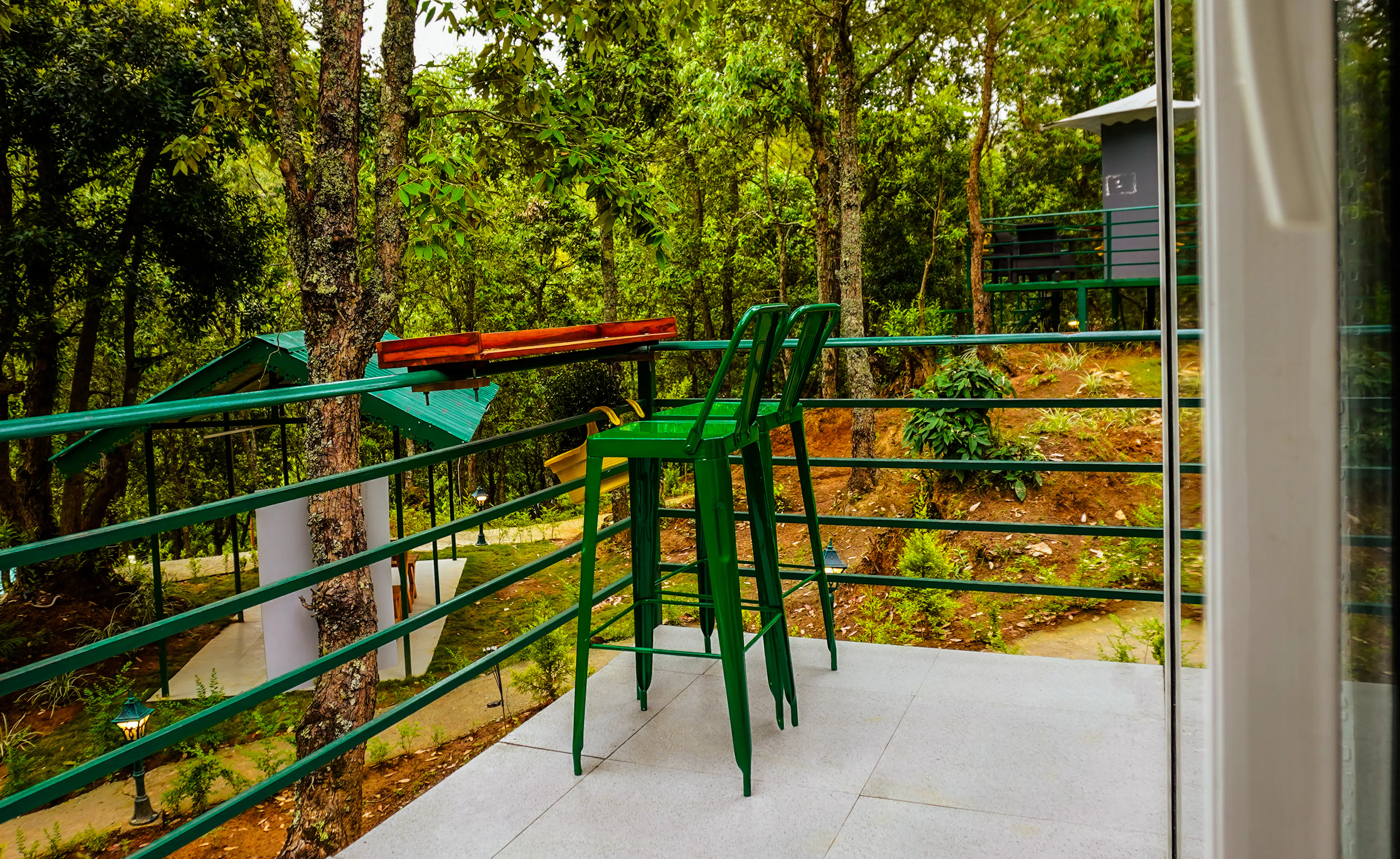 A cottage balcony with bar stools looking into the forest