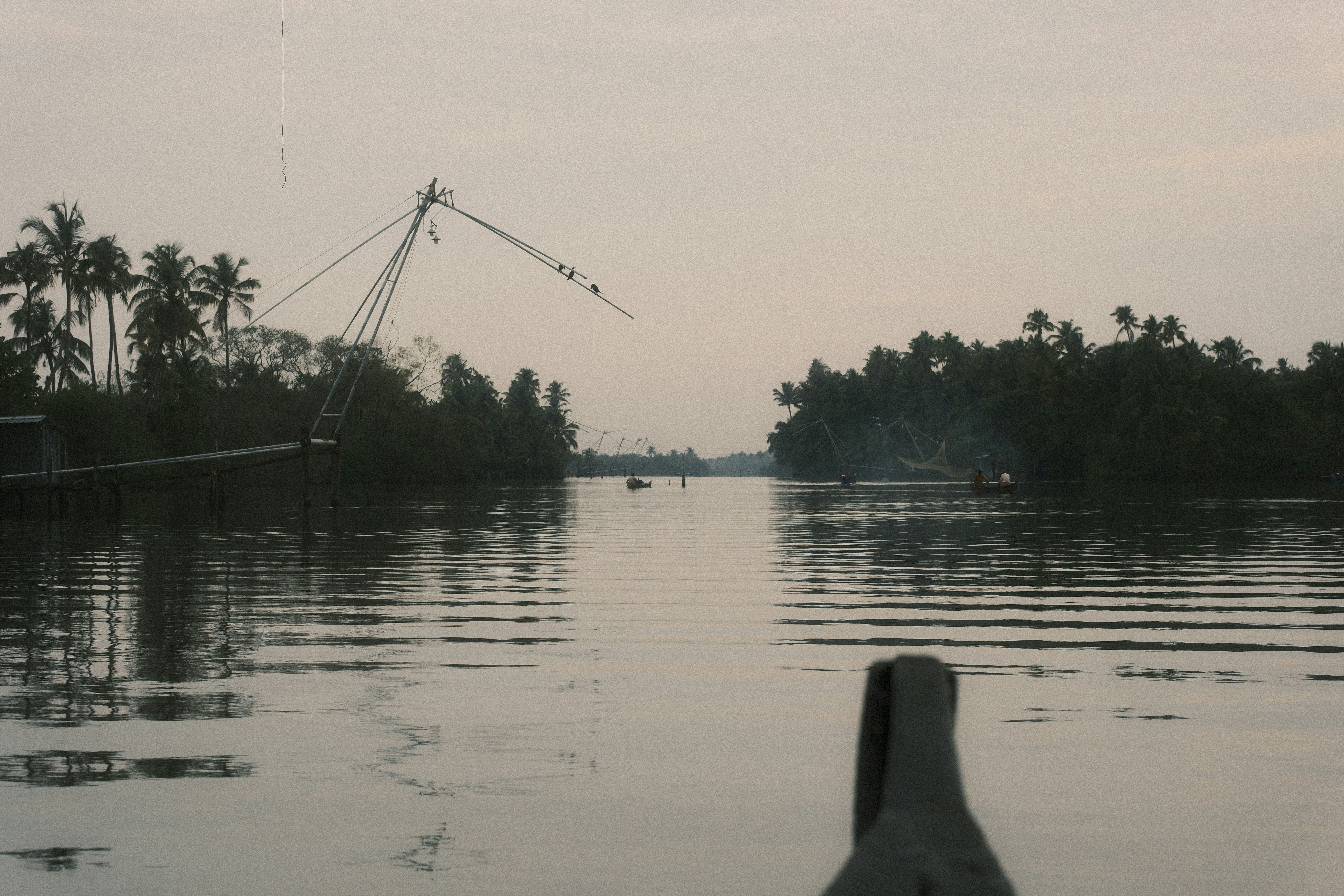 Chinese fishing nets on a calm river lined with palm trees in Kerala