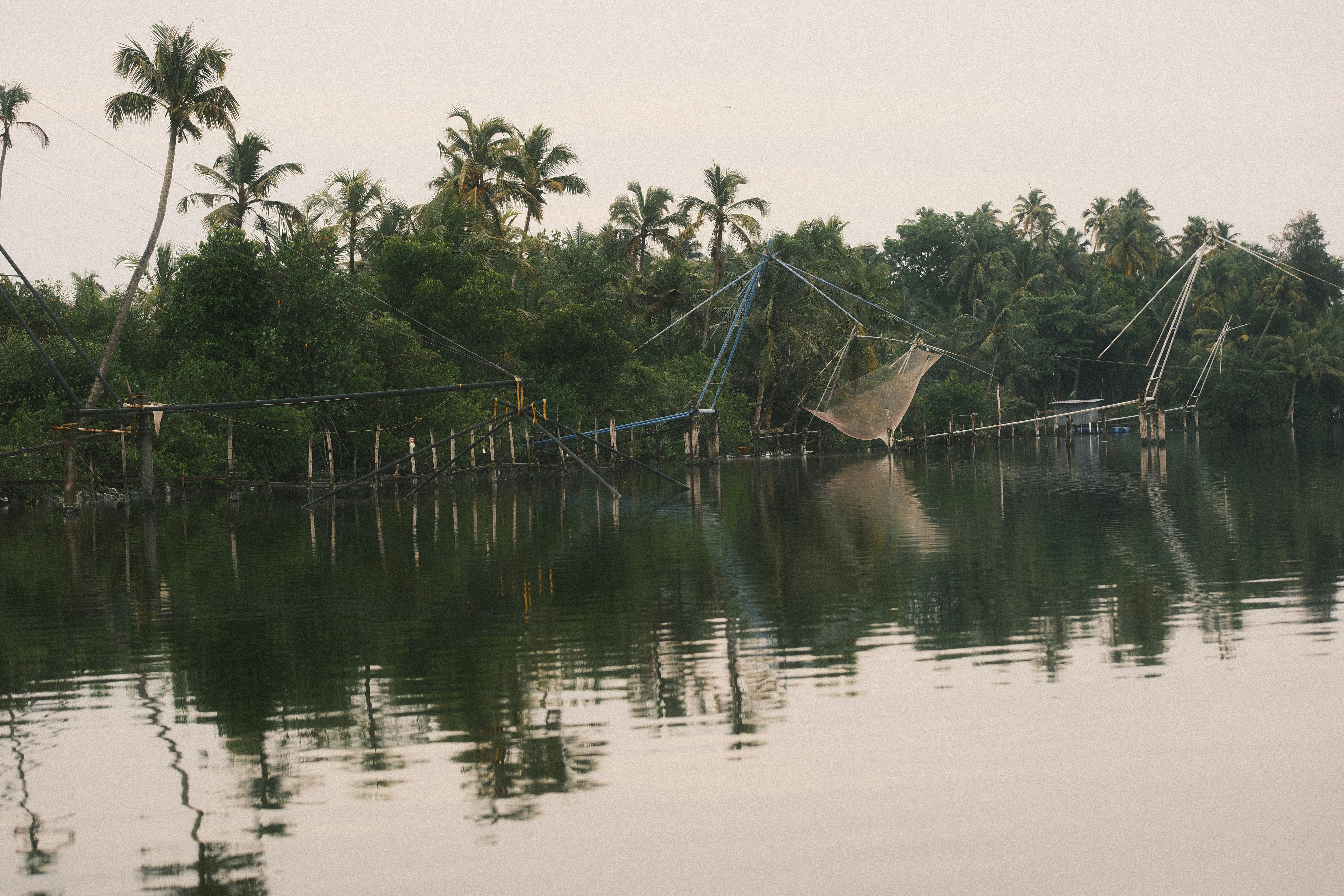 Chinese fishing nets on wooden frames over calm water in Kerala, India