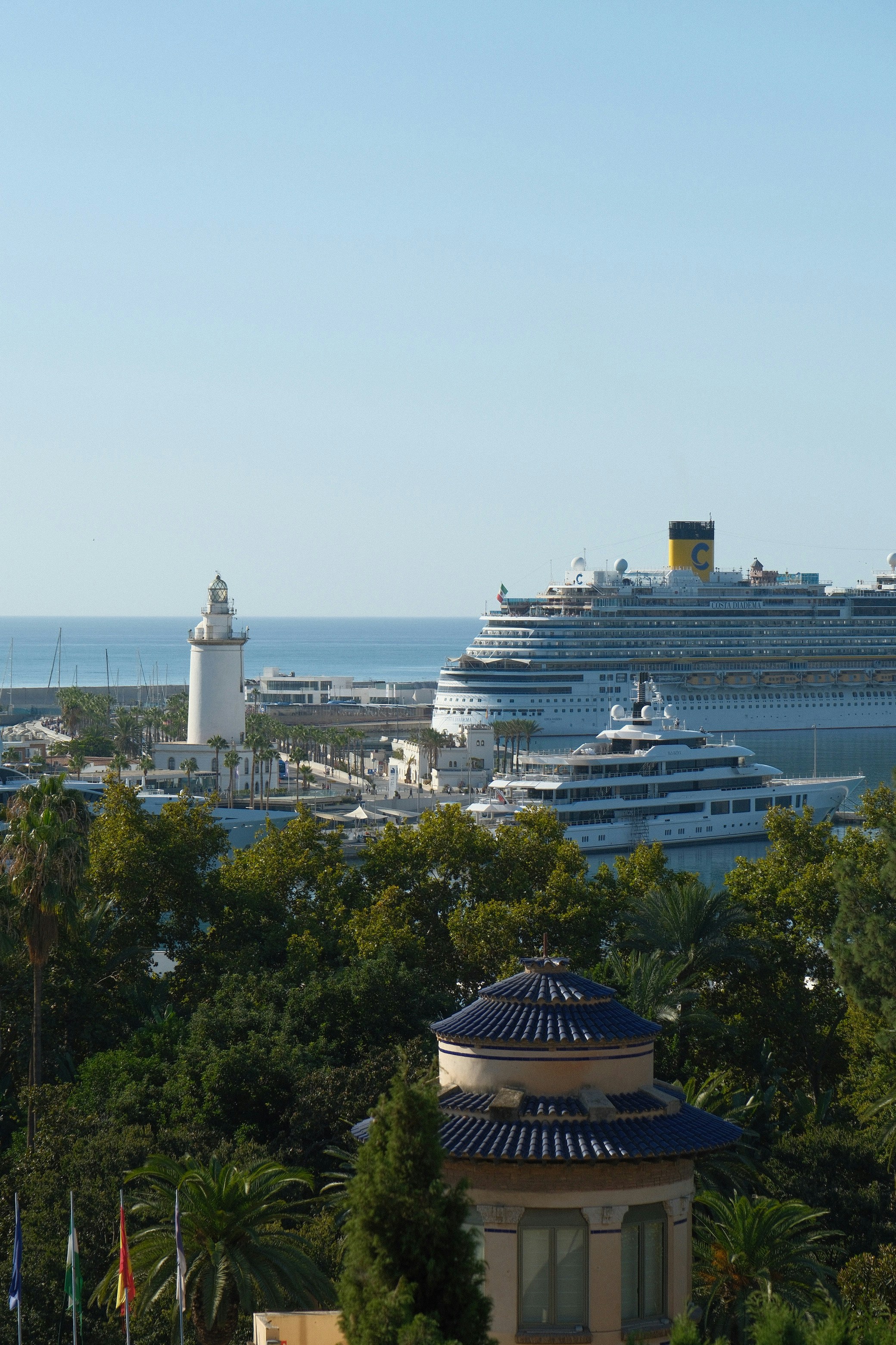 Una nave da crociera e uno yacht attraccati vicino a un faro a Malaga, in Spagna