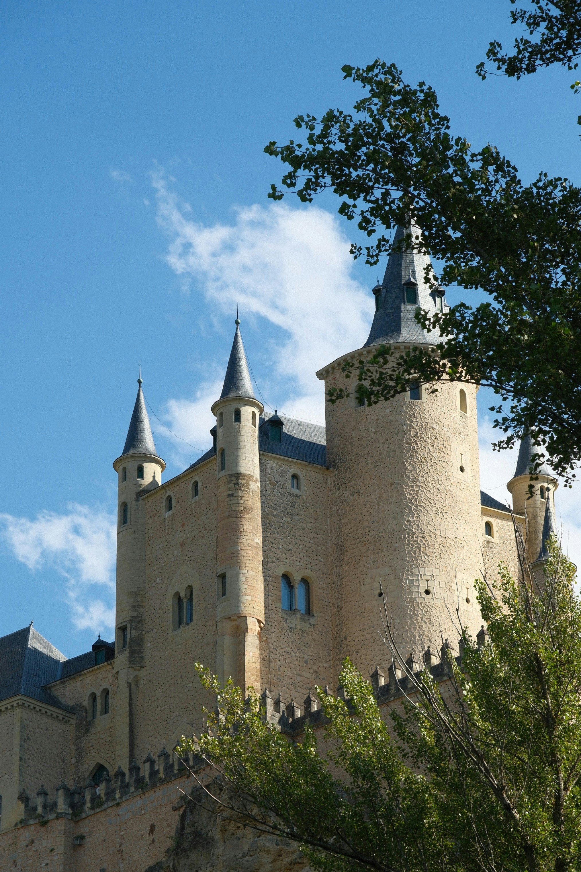 L'Alcázar di Segovia con torri di pietra contro un cielo azzurro brillante