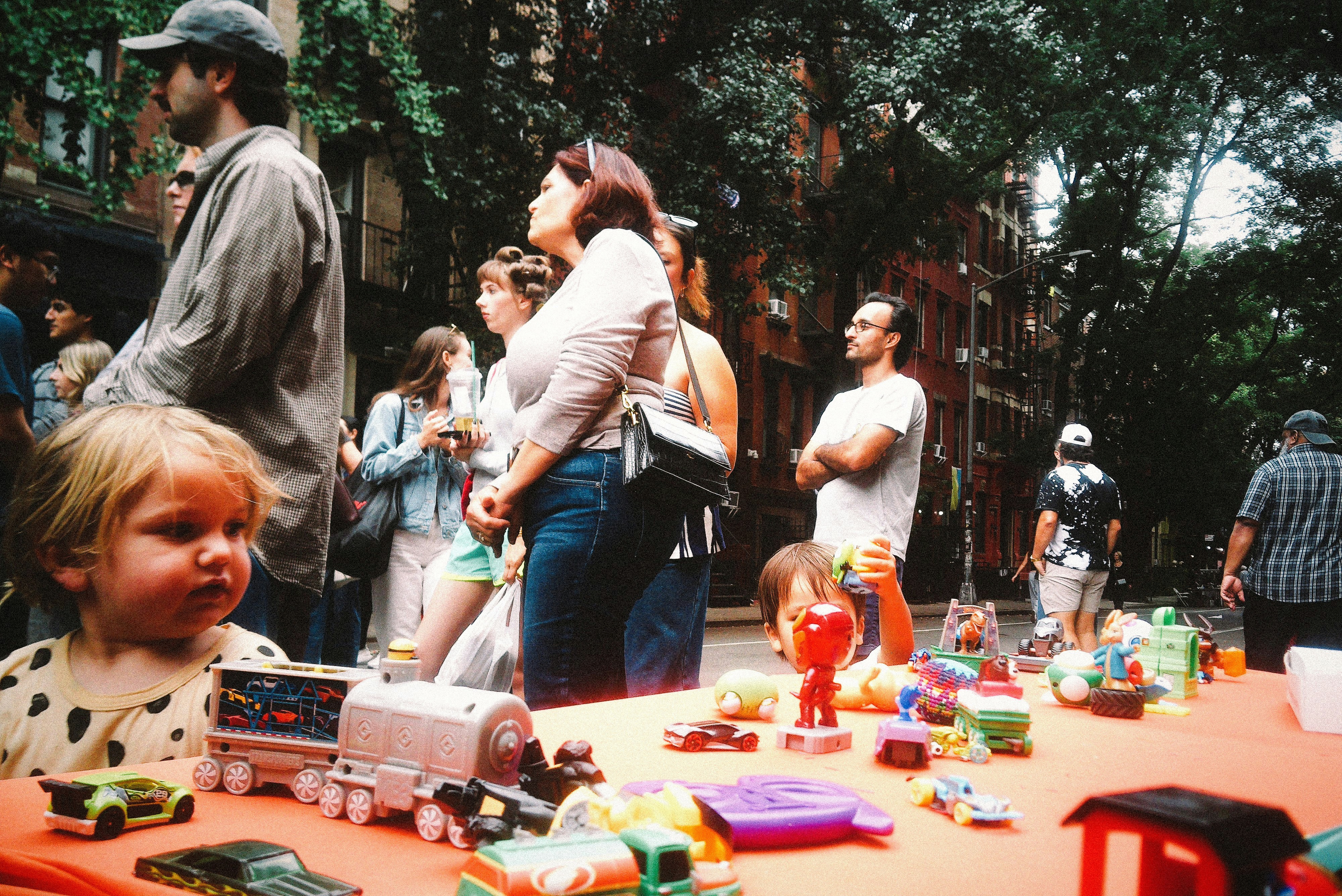 Un enfant regardant une table remplie de petits jouets en plastique dans une rue de la ville
