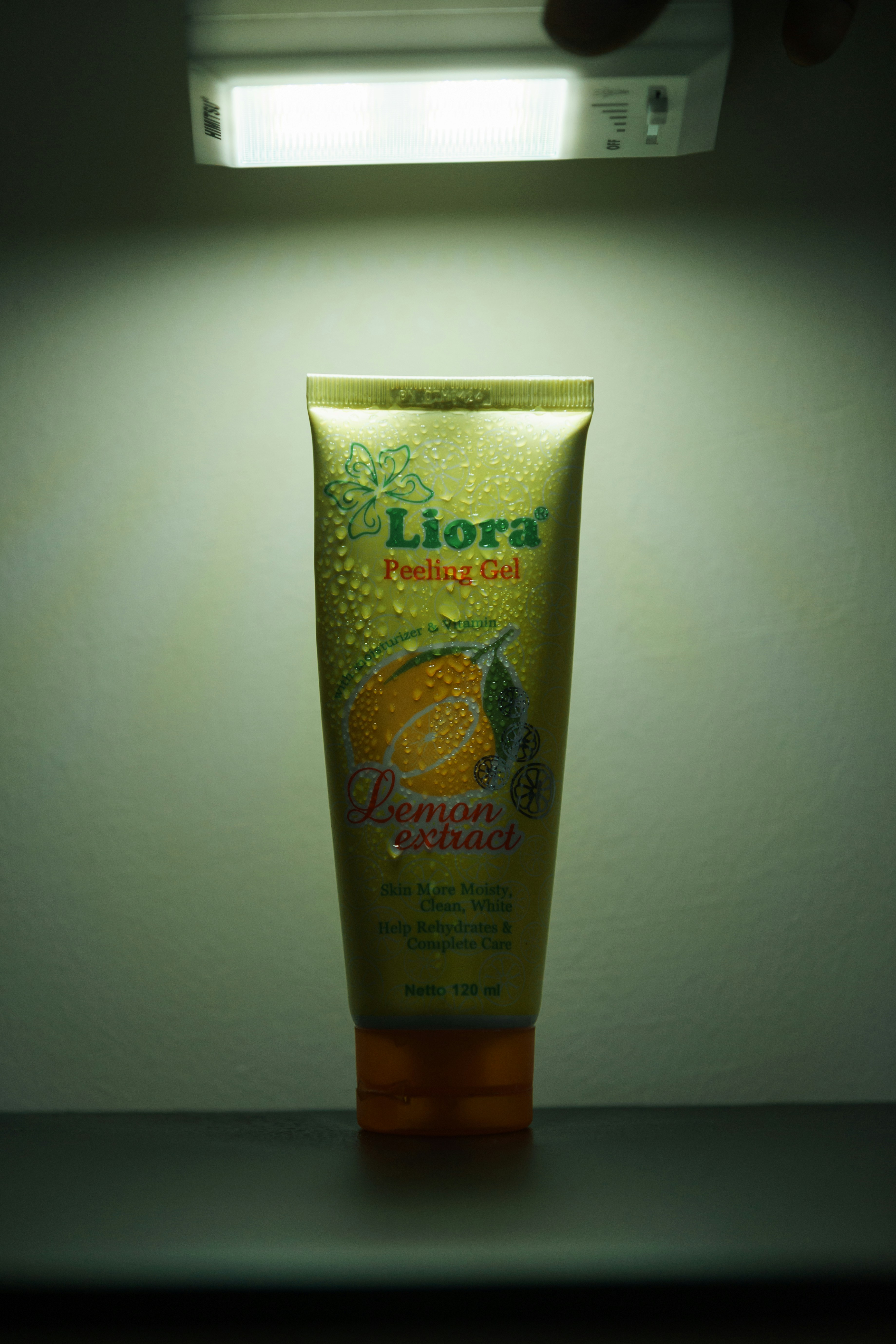Eine Tube Liora-Schälgel mit Wassertropfen unter hellem Licht