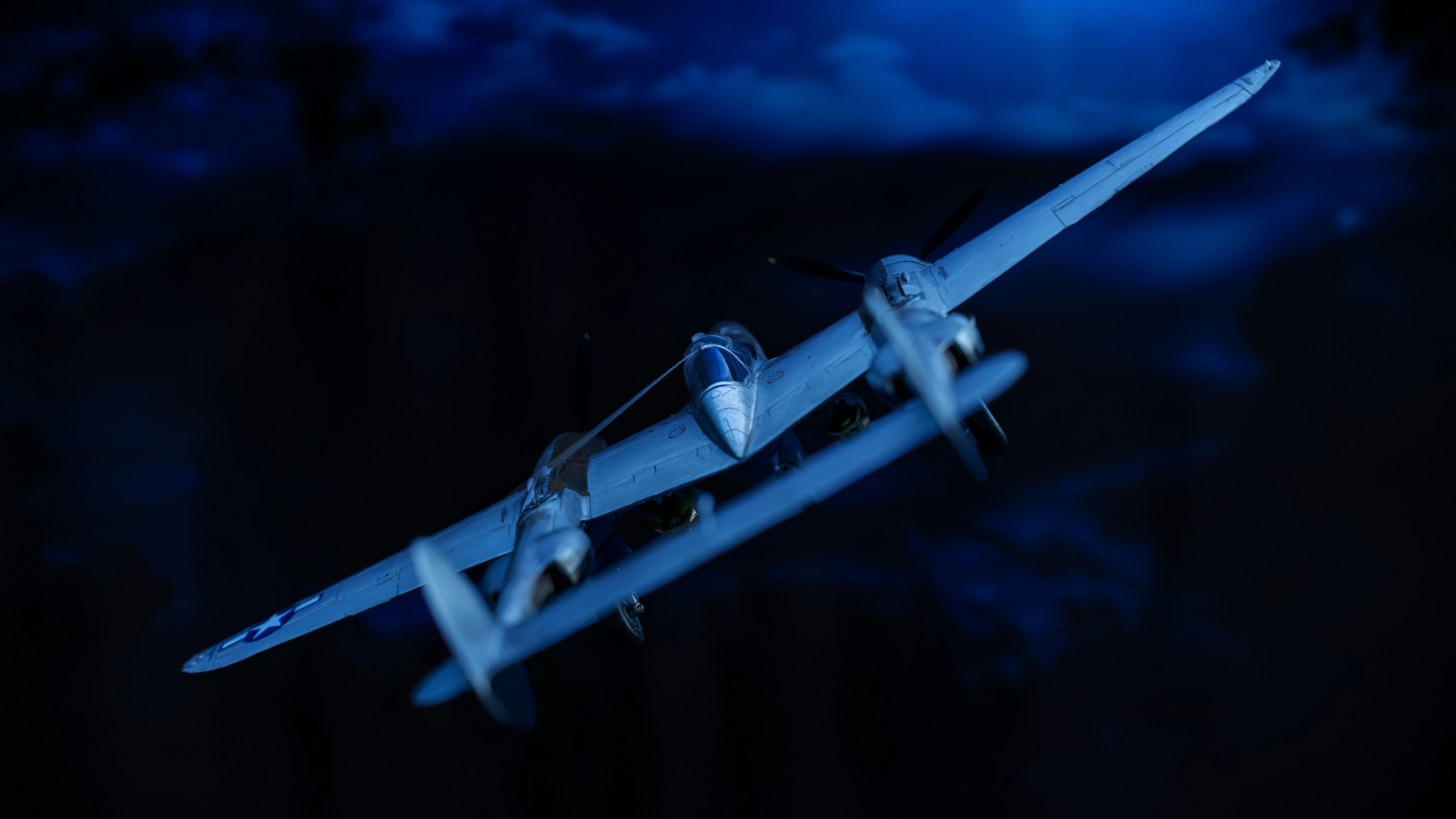 Un avion bimoteur argenté à hélice volant contre un ciel nocturne bleu foncé