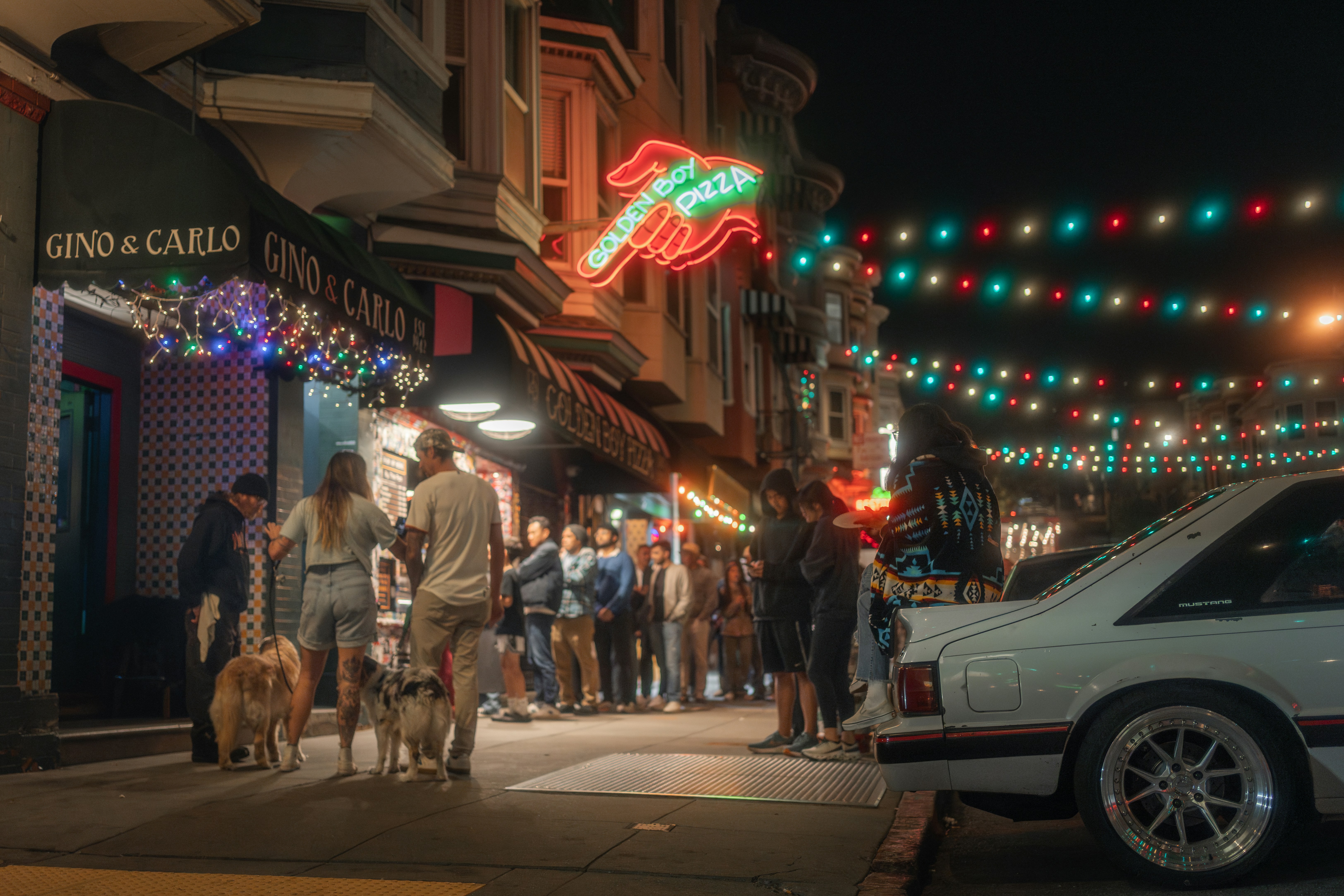 People waiting in line outside Golden Boy Pizza and Gino and Carlo at night