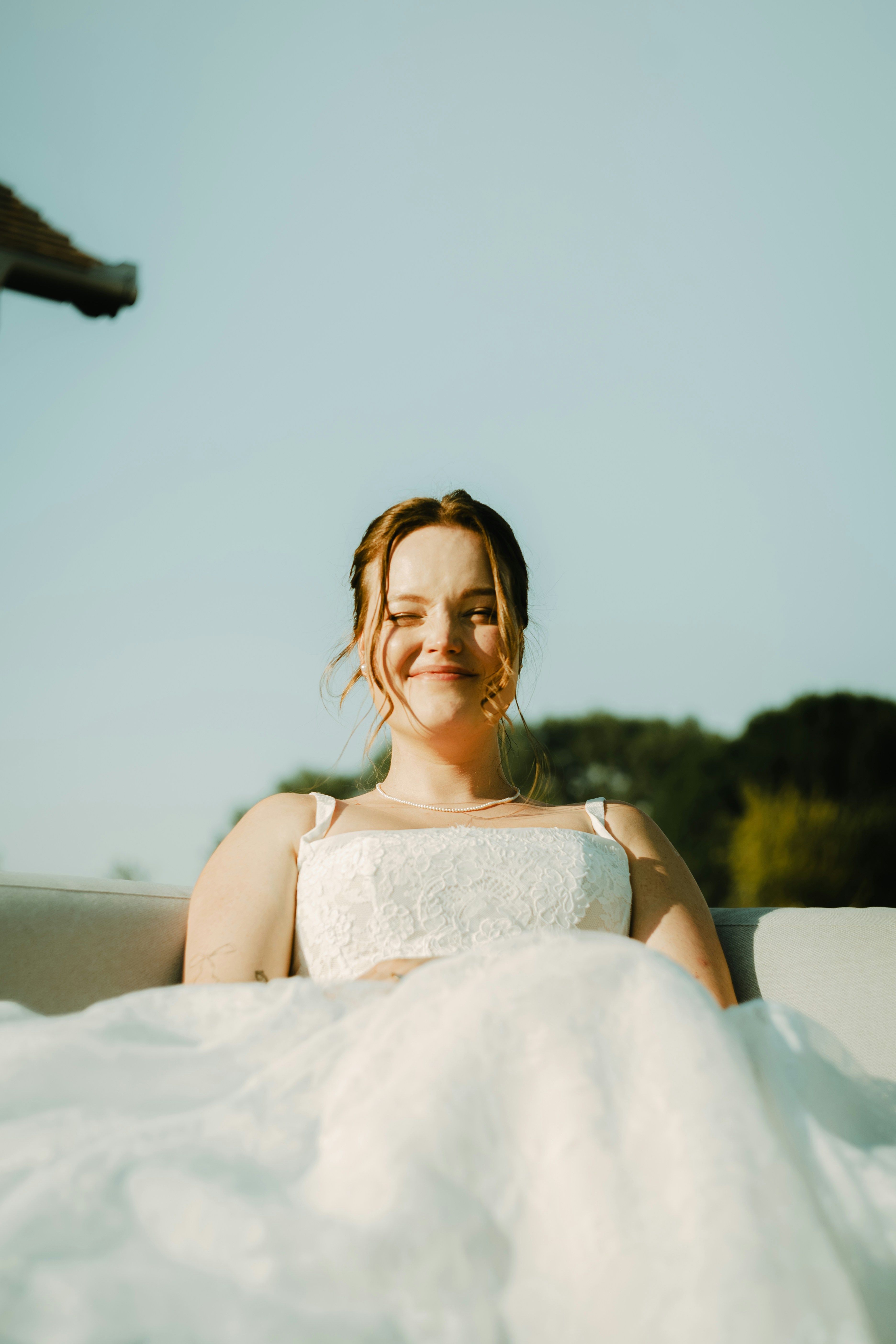 A woman in a white lace dress with a pearl necklace outdoors