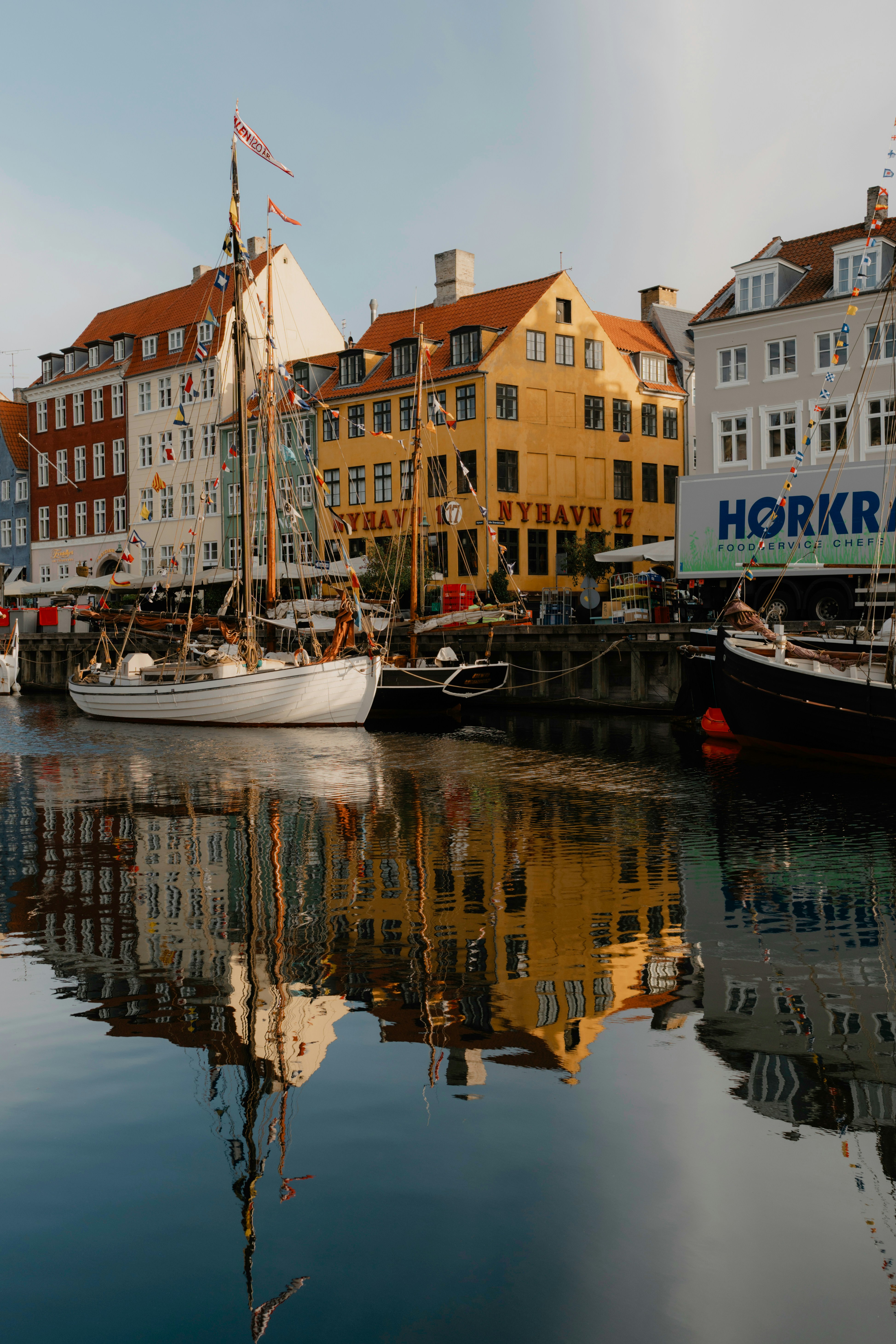 Wooden sailing boats moored in Nyhavn canal with colorful historic buildings in Copenhagen
