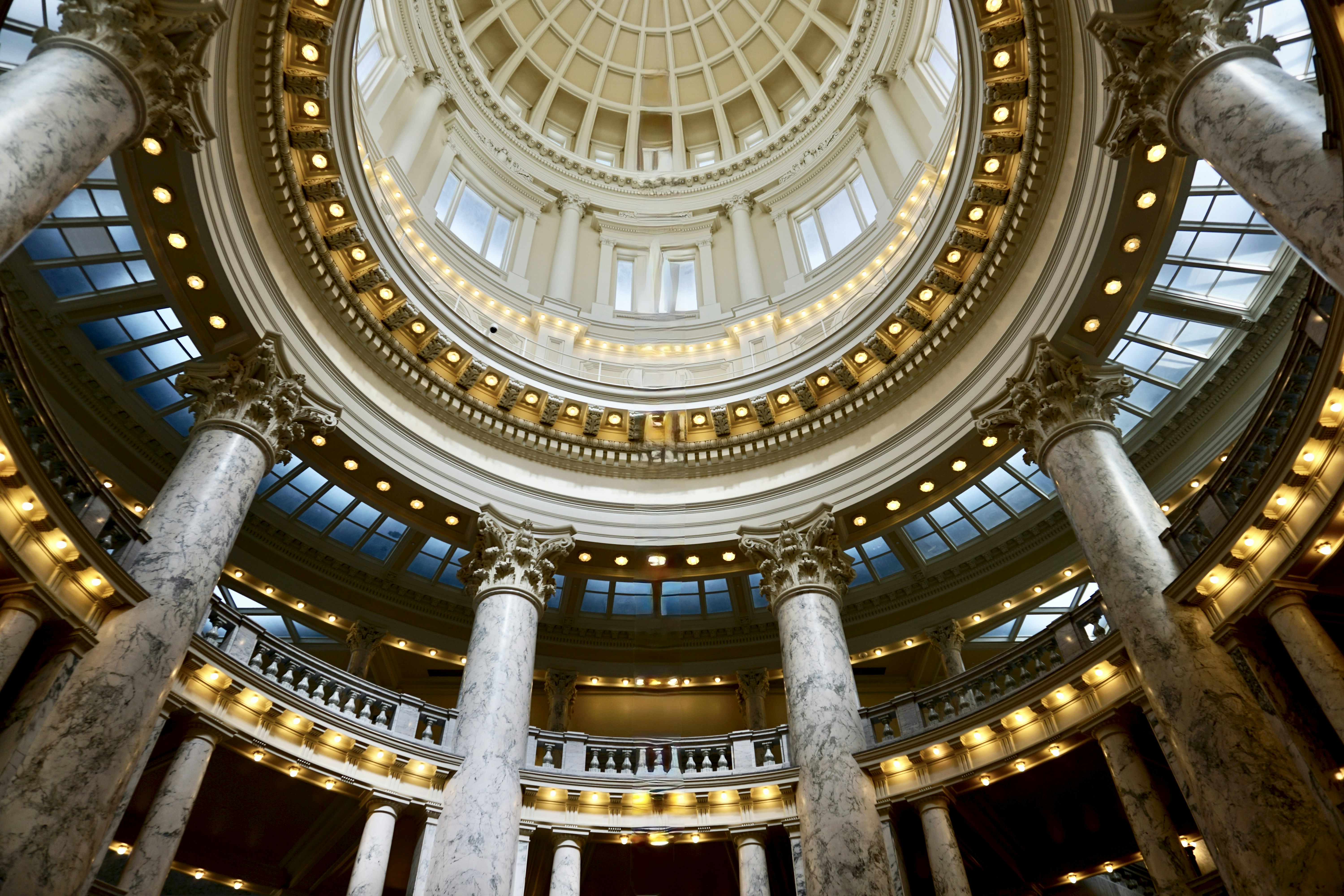 The ornate rotunda of a capitol building with marble columns and a domed ceiling
