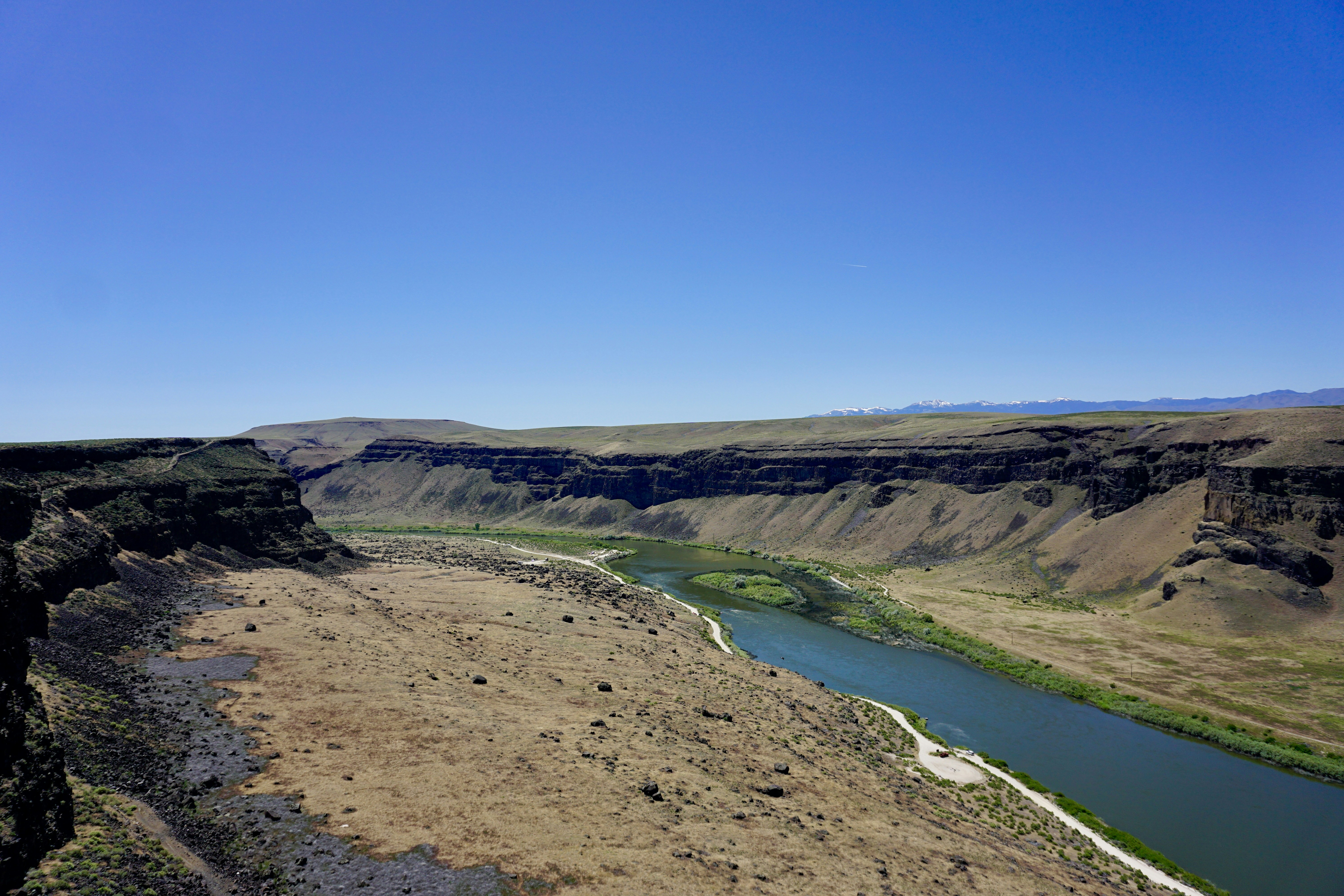 A winding river flowing through a deep canyon with dry grassy slopes