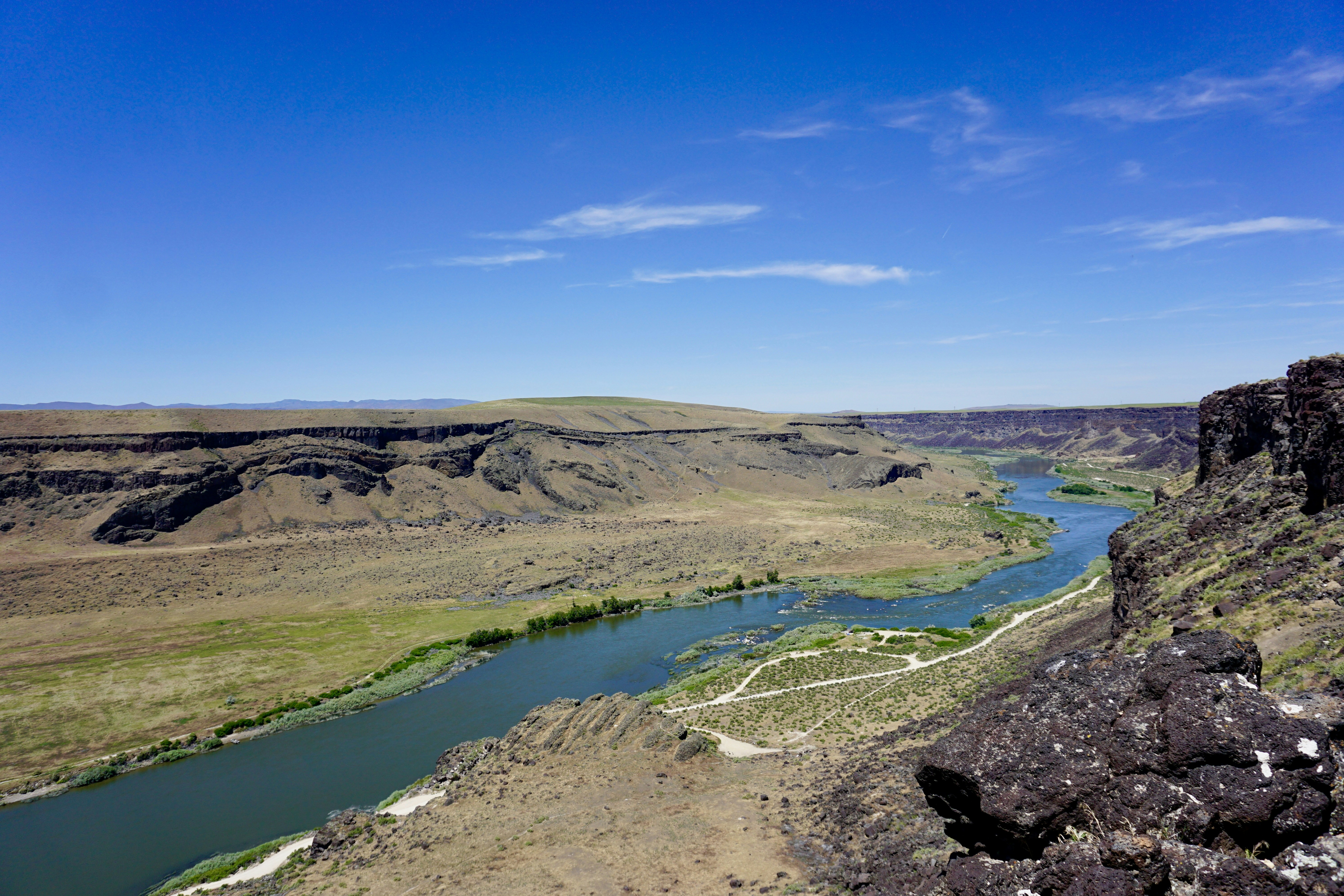 A winding river through a deep canyon with rocky cliffs under a blue sky