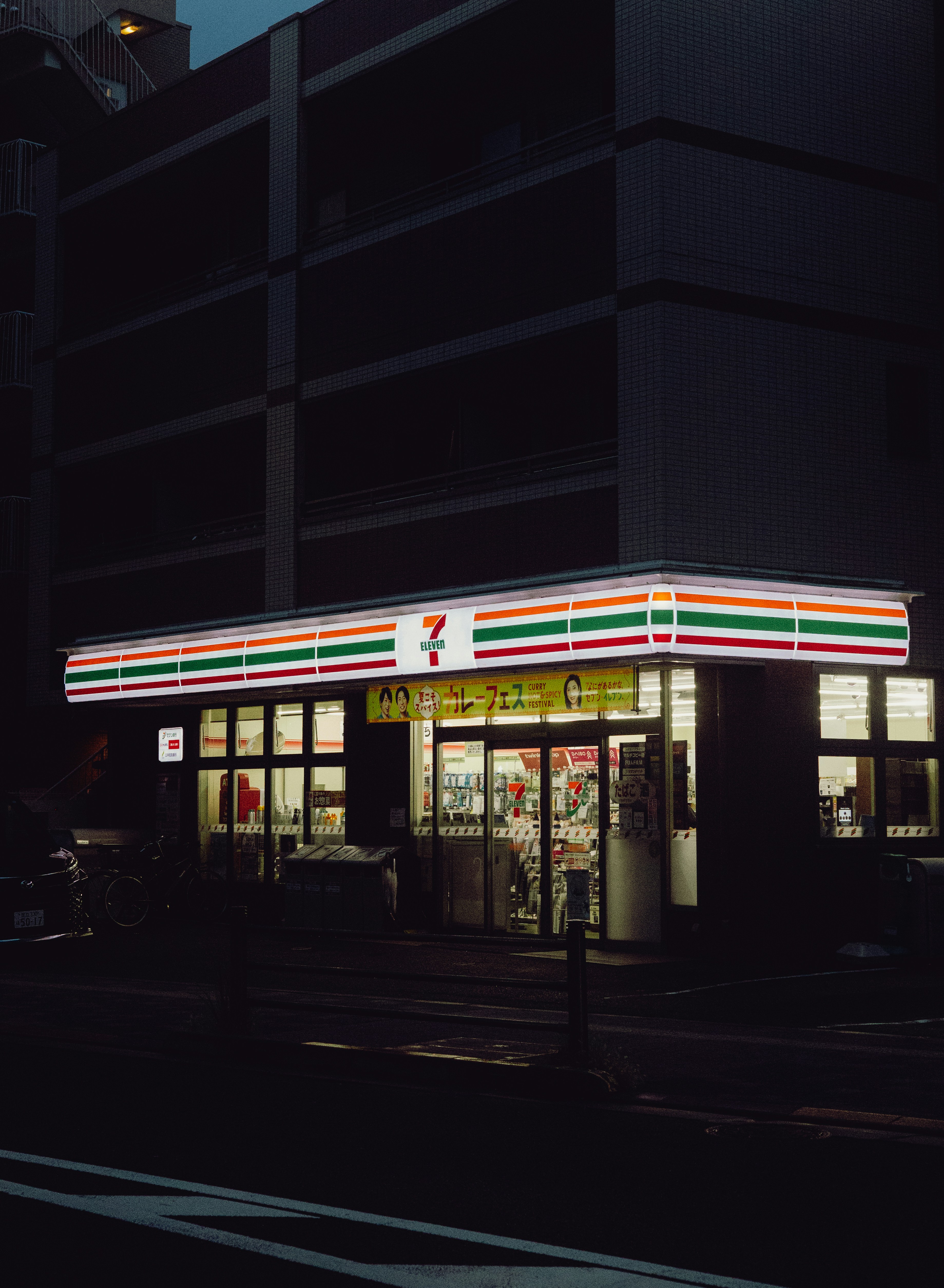 A 7-Eleven convenience store illuminated at night on a dark city street