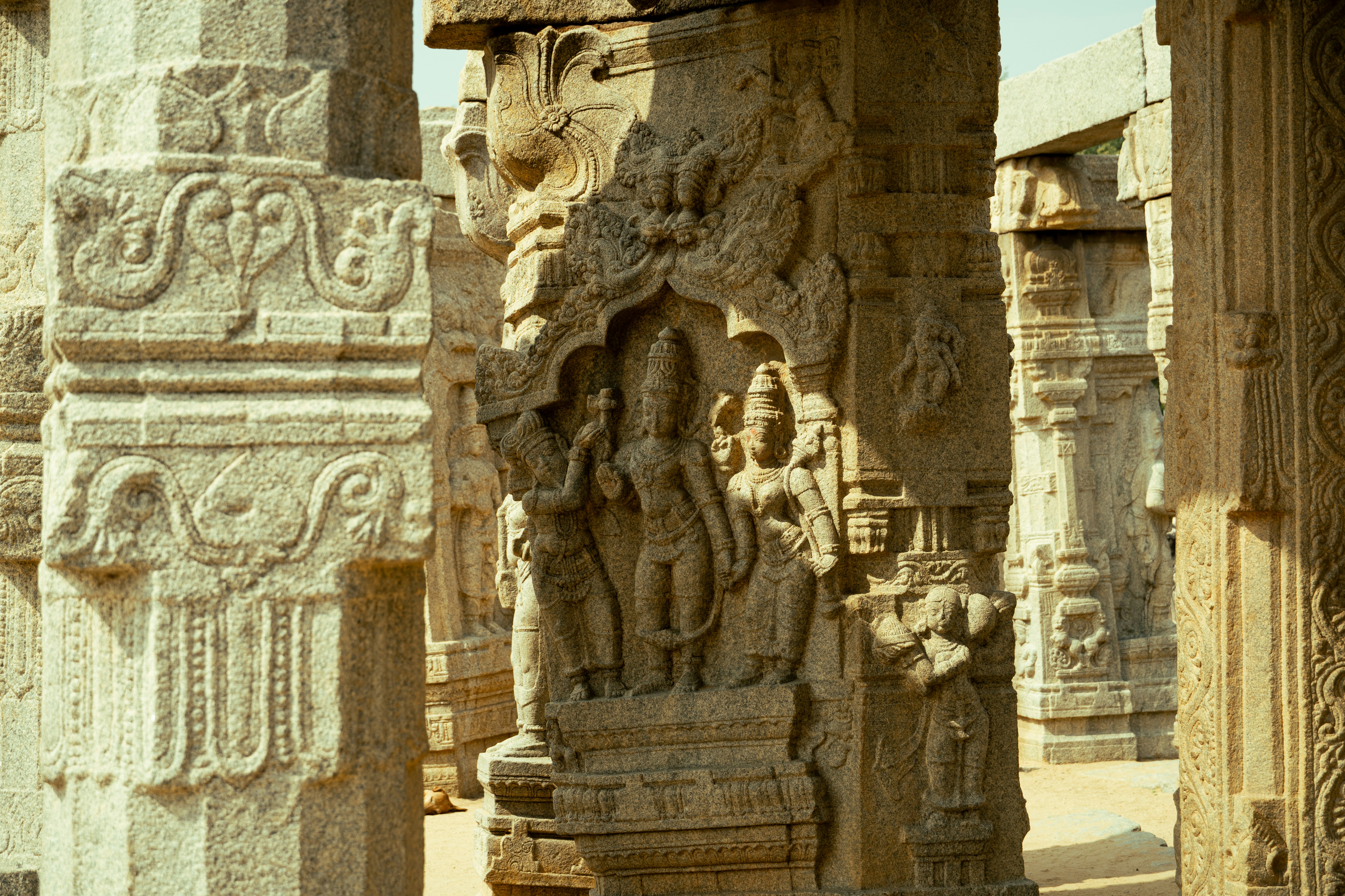 Intricate stone carvings of figures on a pillar in the Lepakshi temple