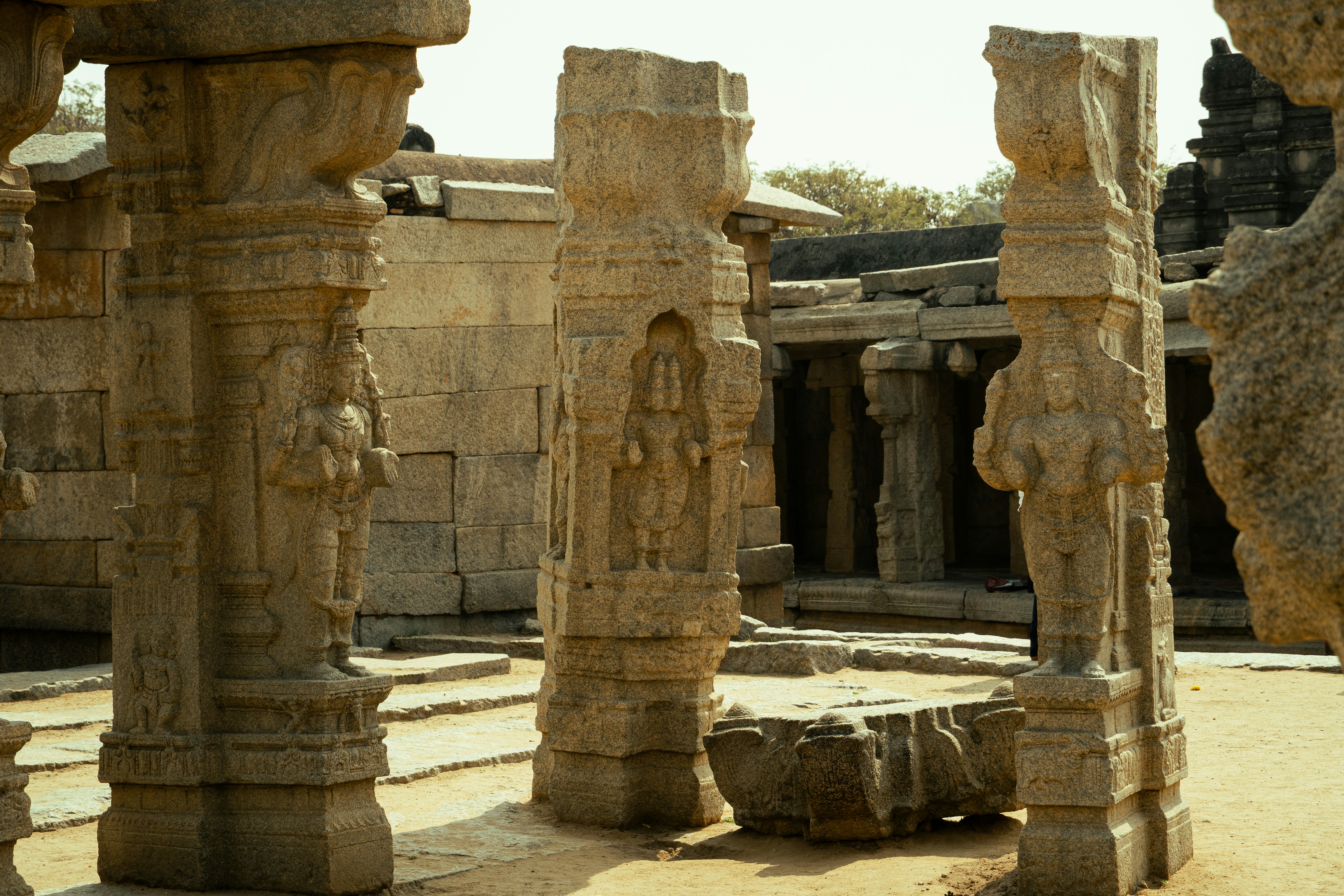 Carved stone pillars with human figures in the ancient ruins of Hampi, India