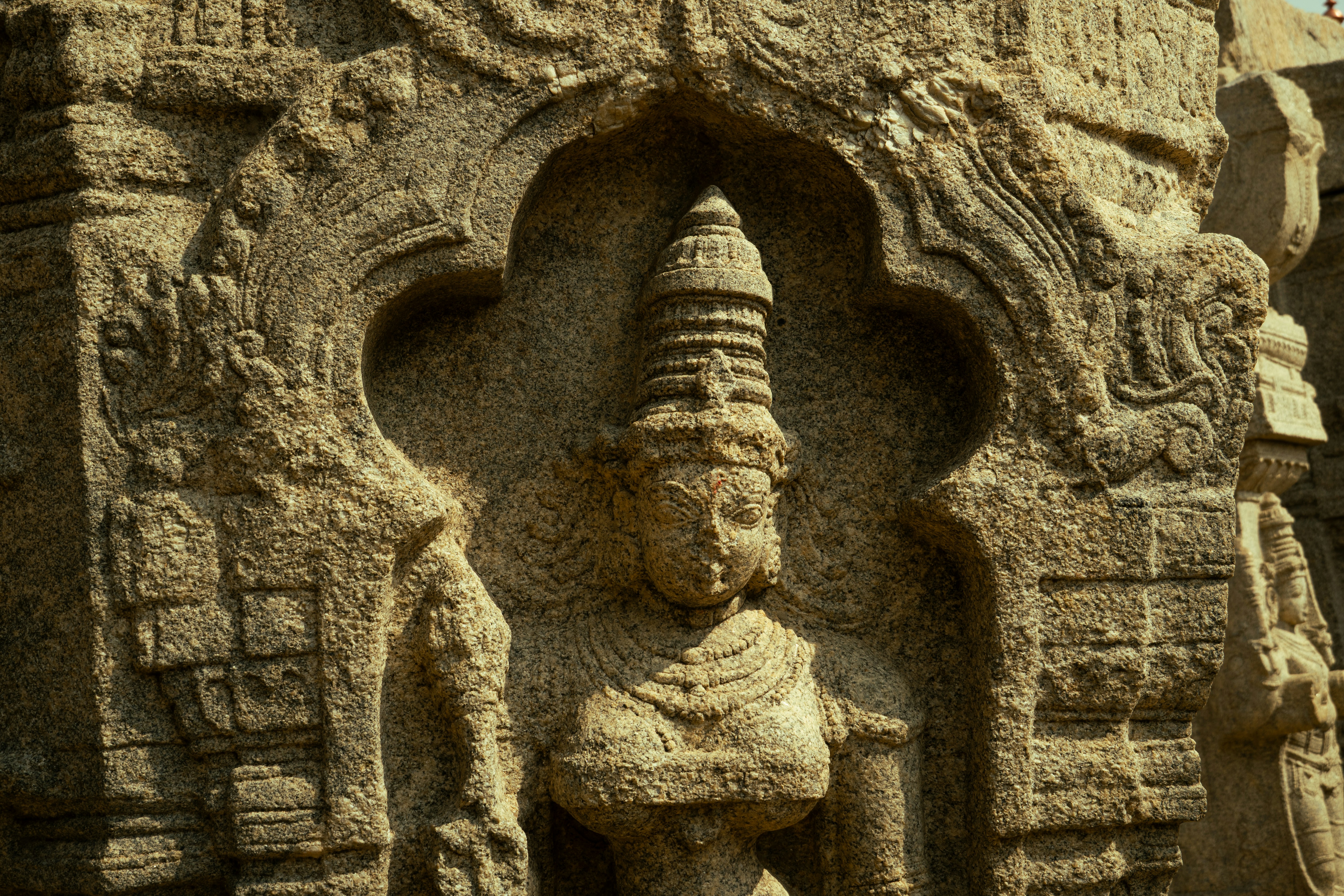 A stone relief carving of a figure with an ornate headdress in a niche