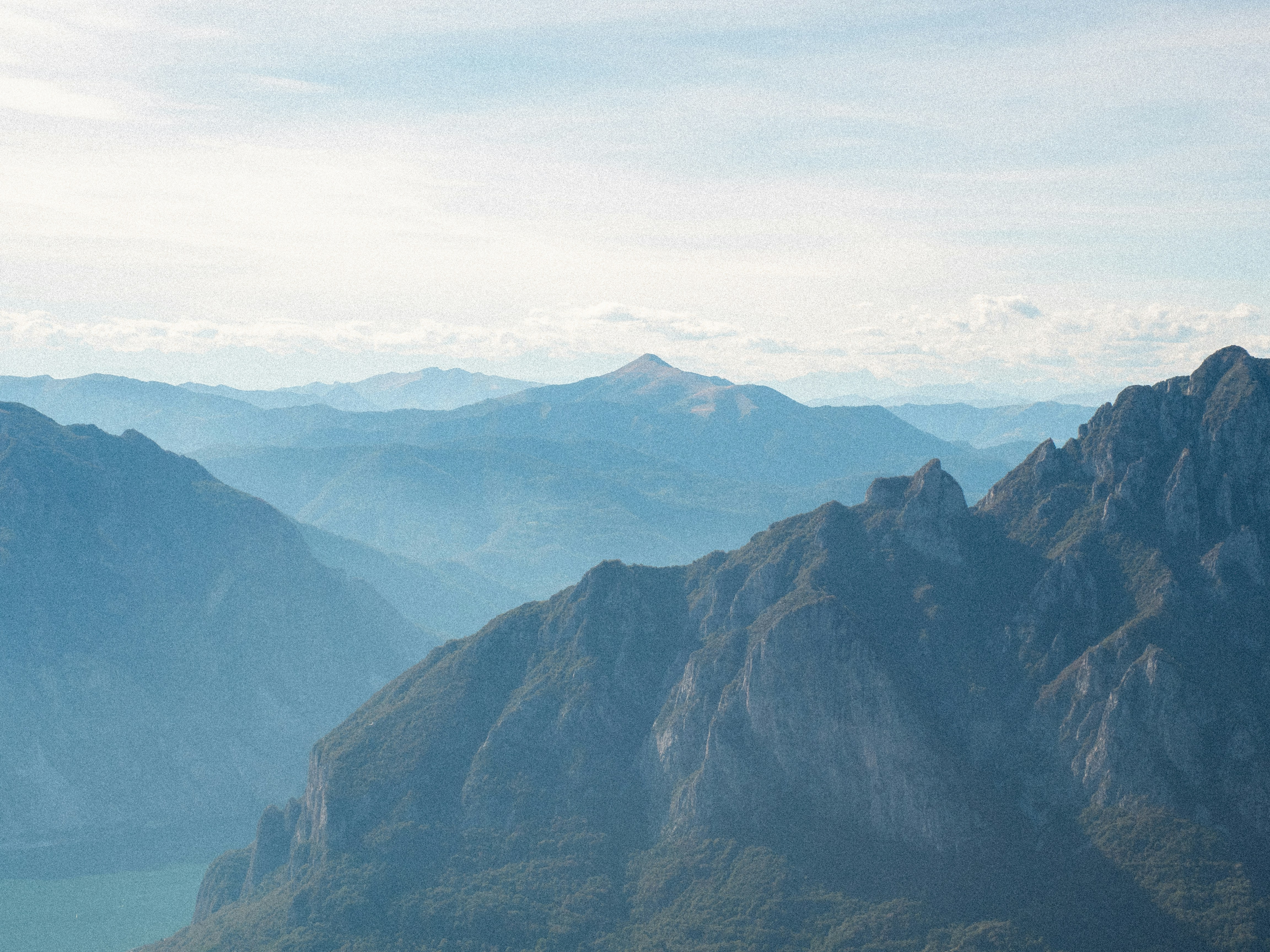 Layered blue mountain ridges fading into a hazy distance under a pale sky