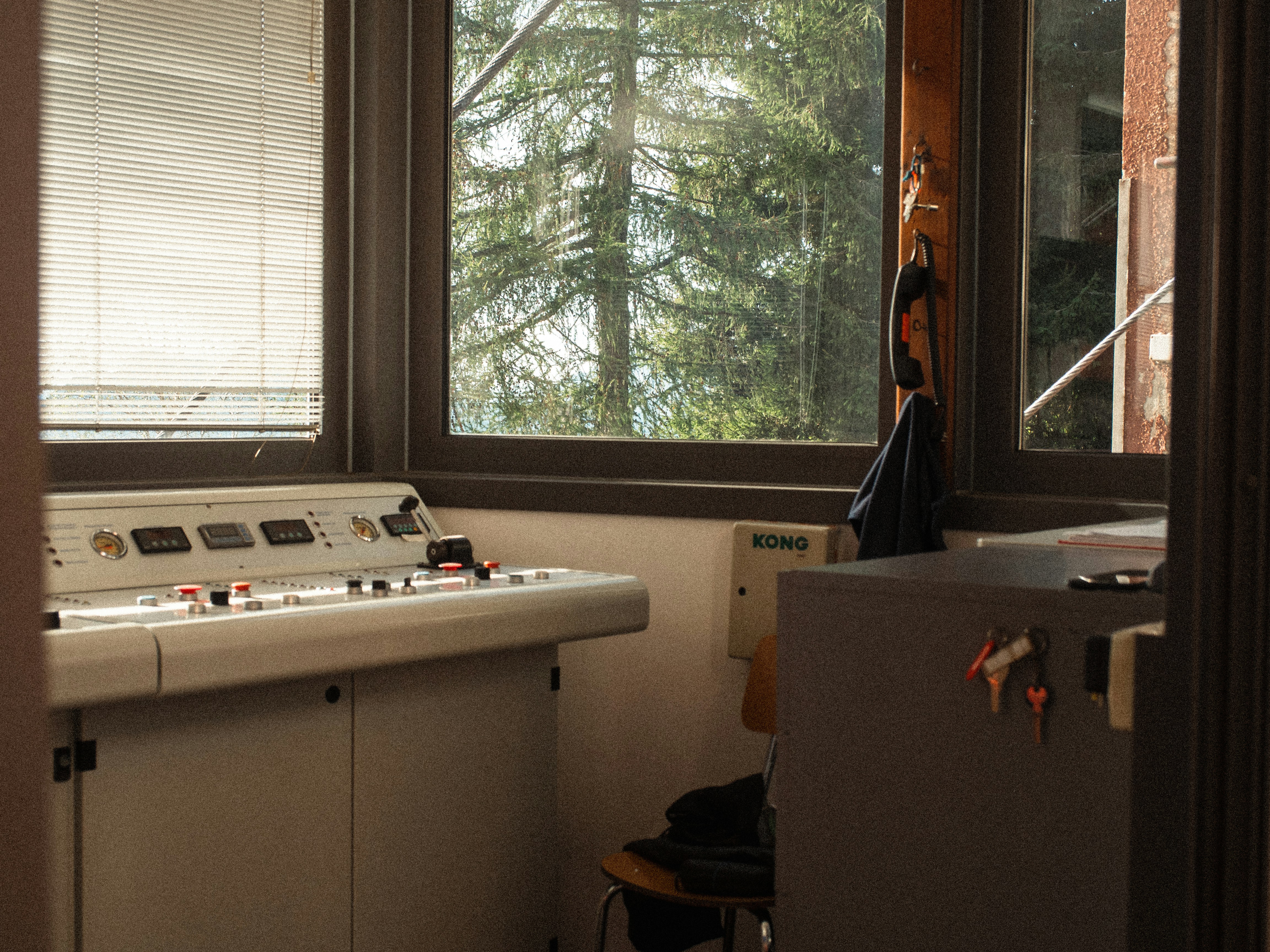 A control console with buttons and gauges in a room overlooking pine trees