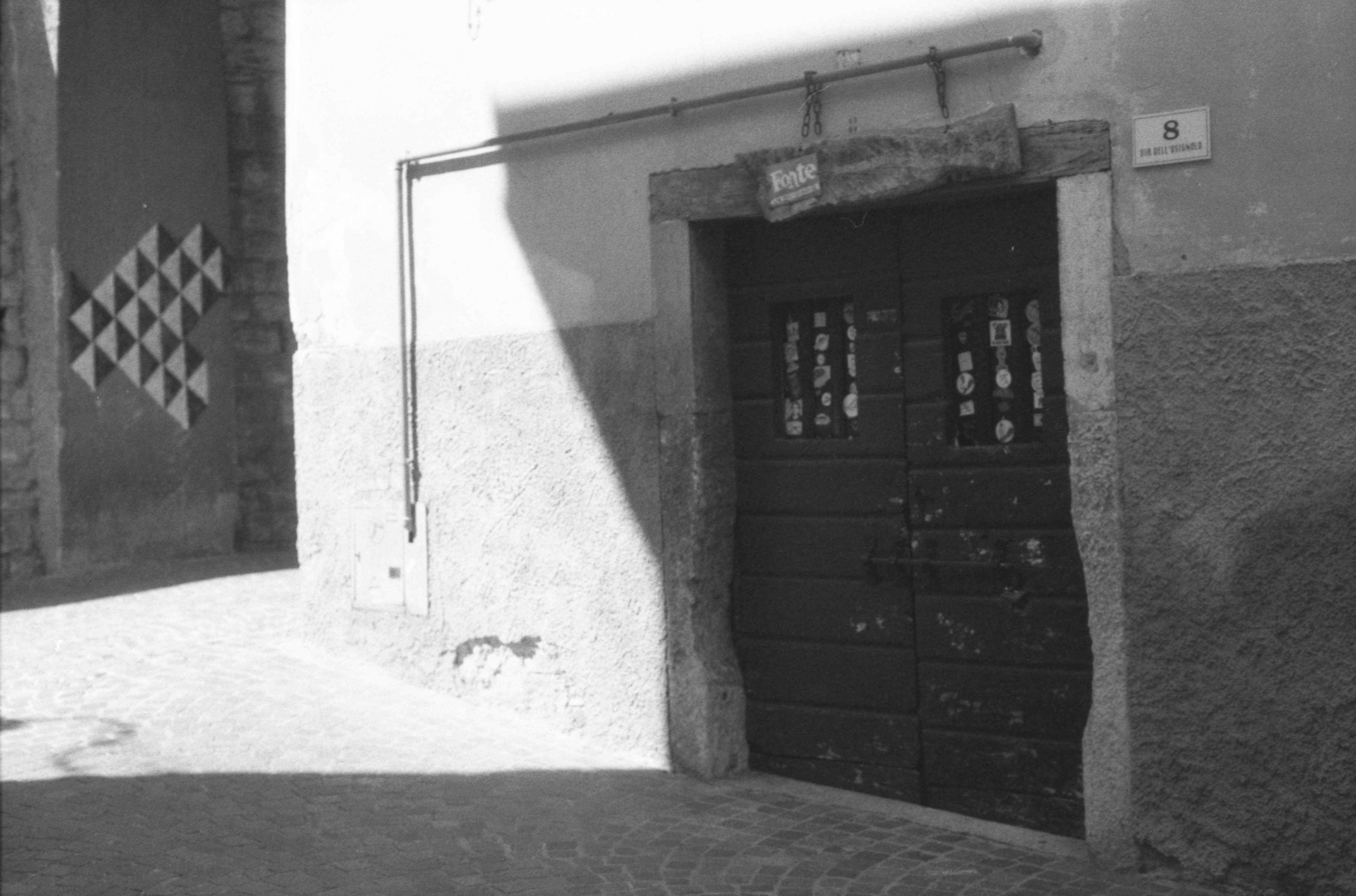 A dark wooden door with small windows in a textured stone wall