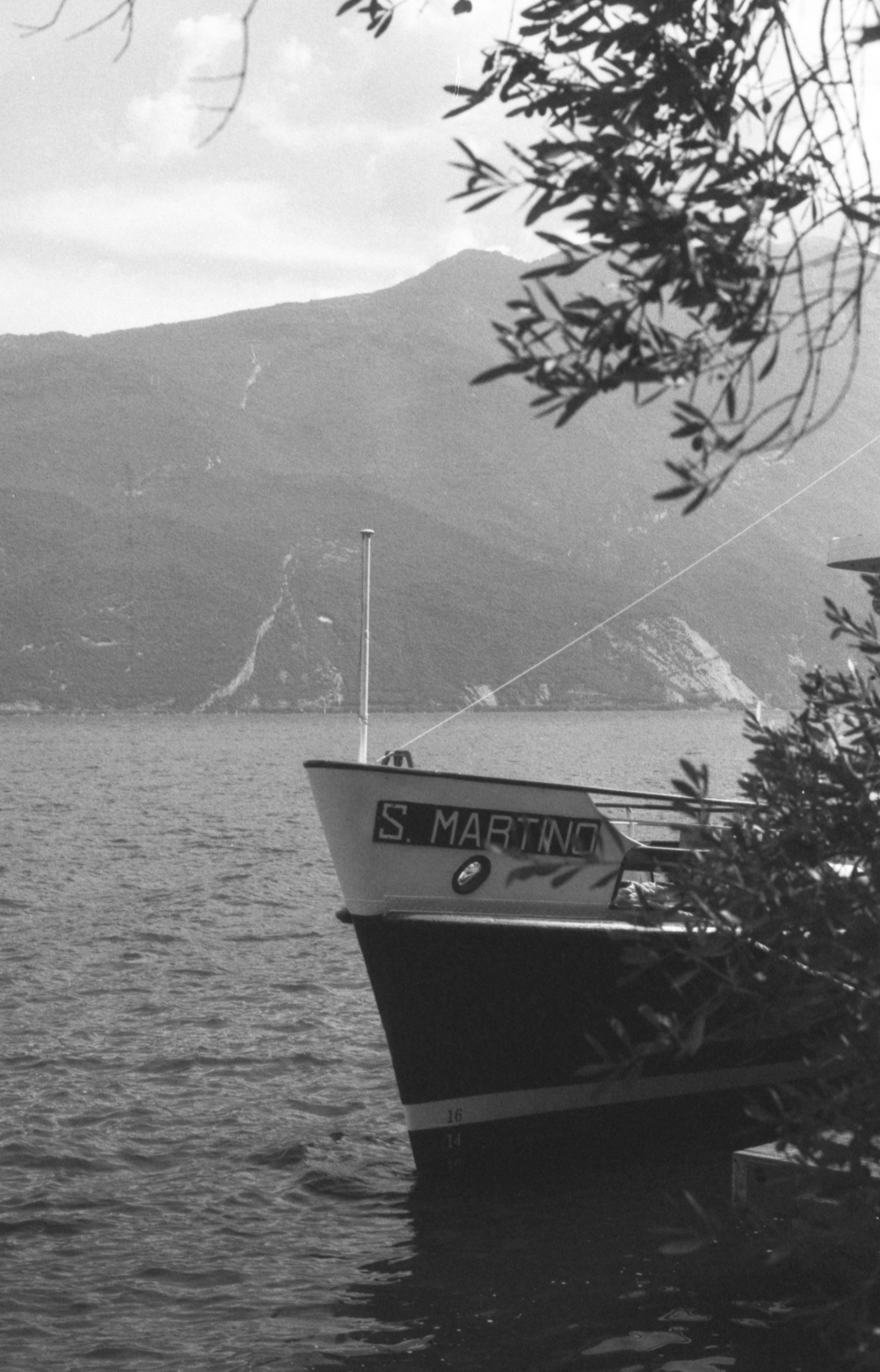 A boat named S. MARTINO on a lake with mountains in the background