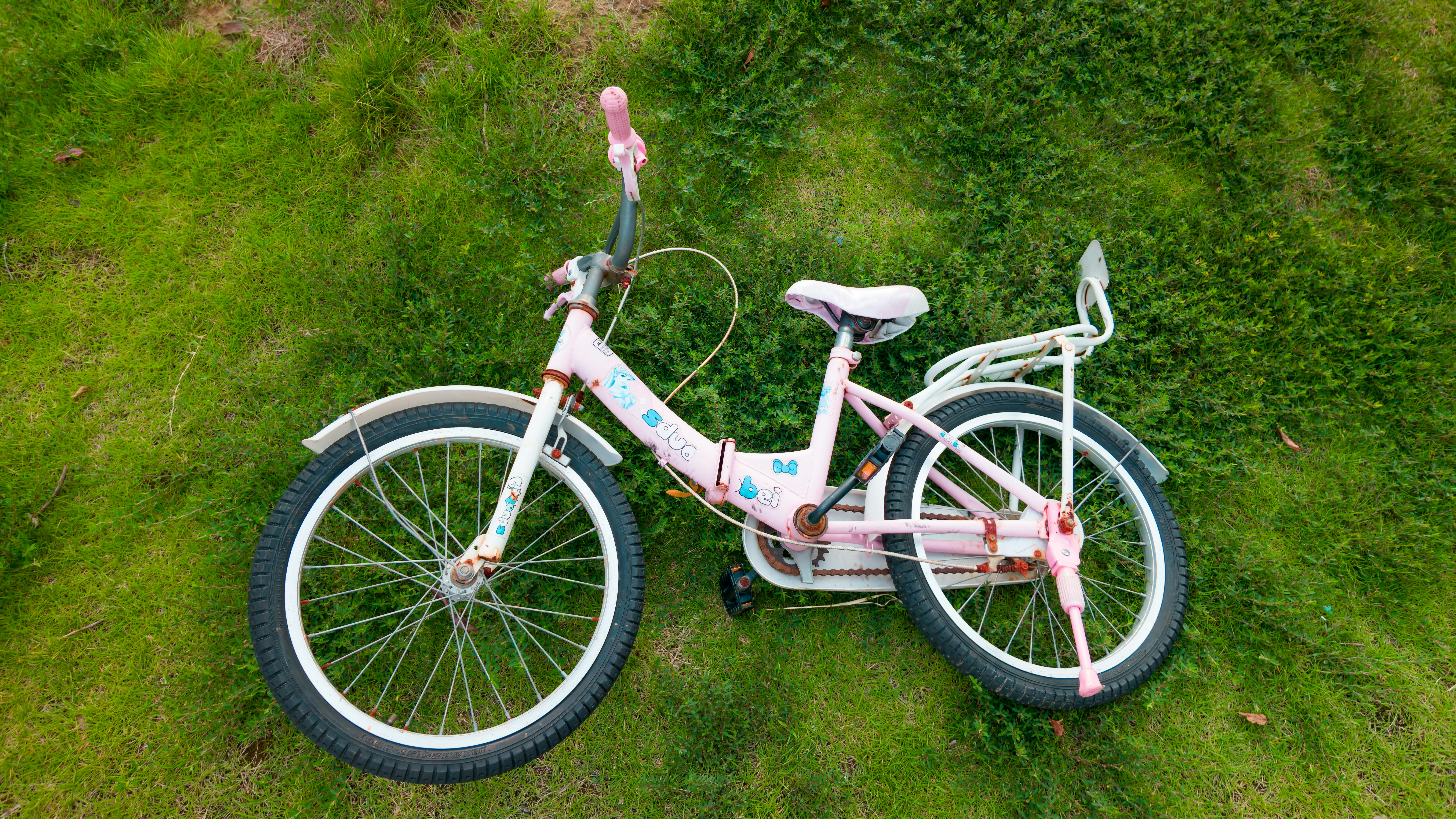 A pink child's bicycle lying on a patch of green grass