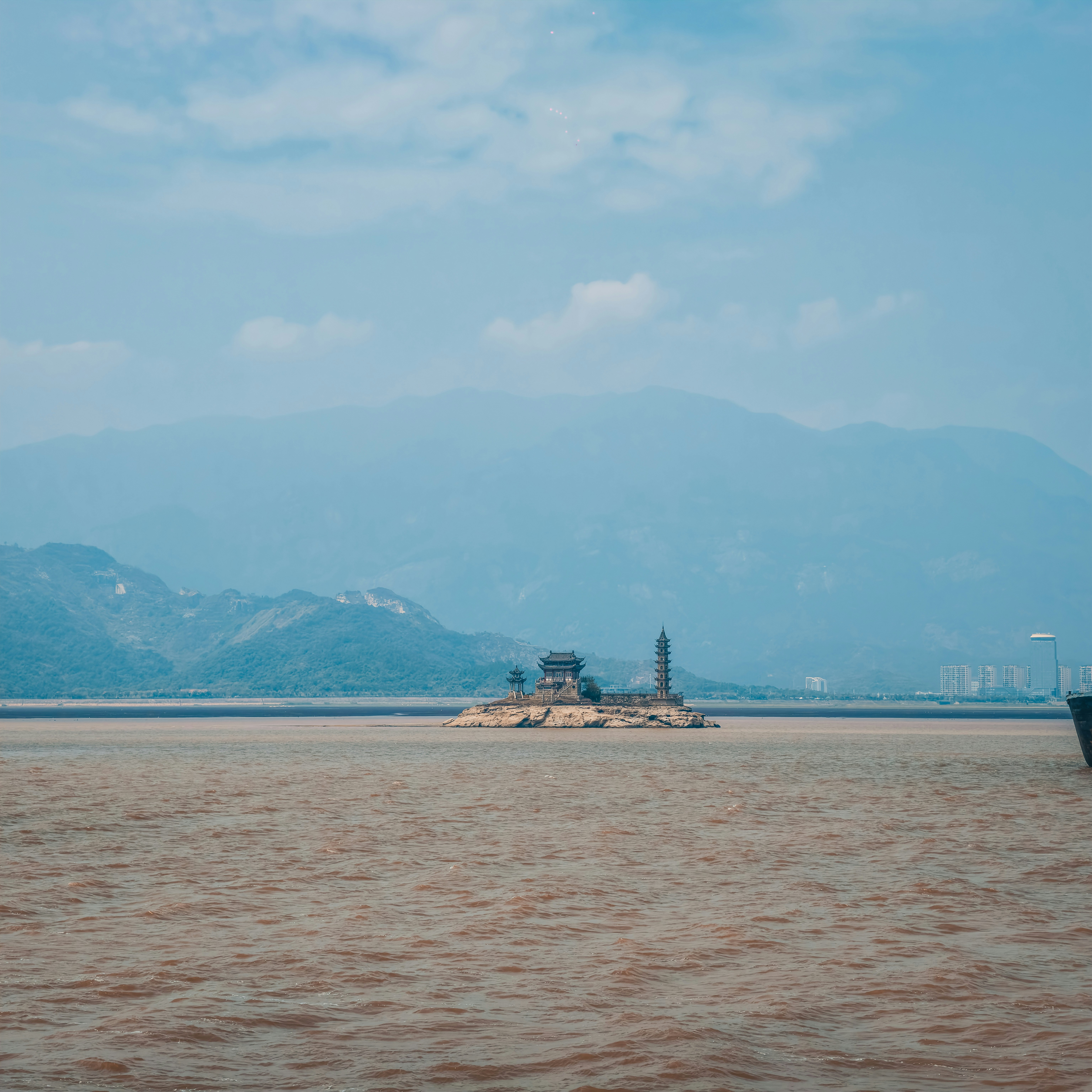 A small island with a pagoda and temple in a wide river
