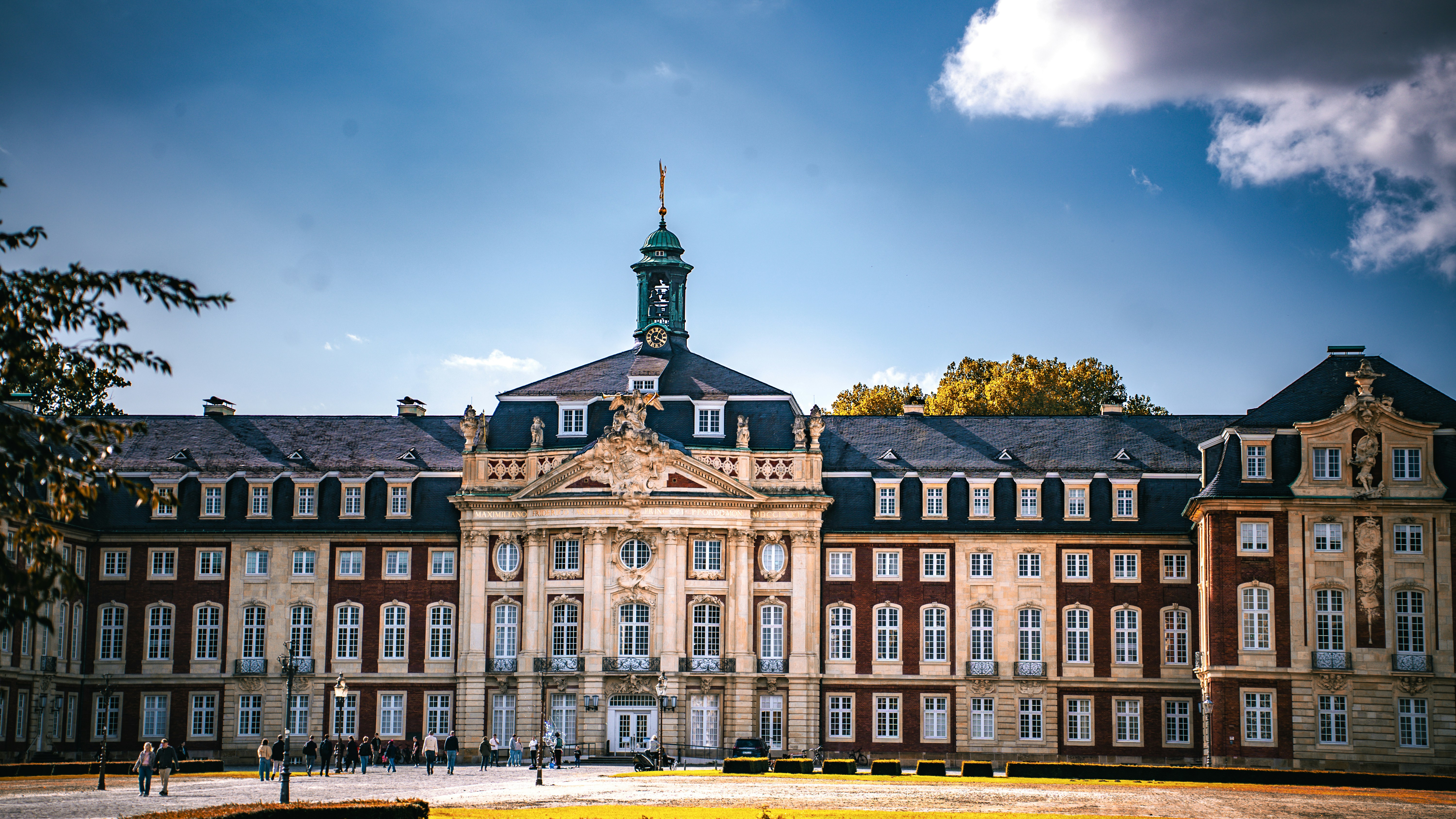 The Prince-Bishop's Palace in Münster with people walking on the gravel courtyard