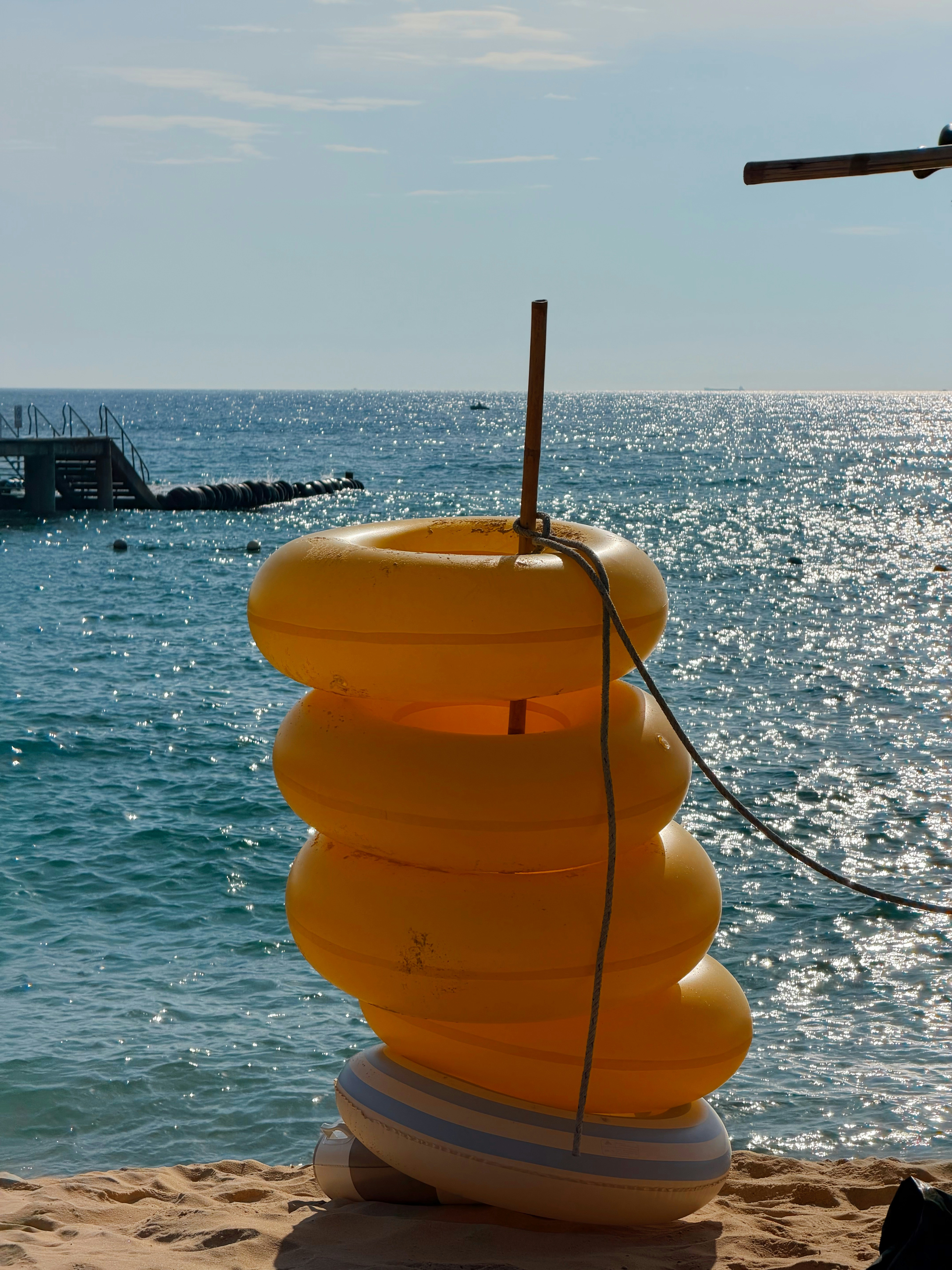 A stack of yellow inflatable swim rings on a sandy beach by the sea