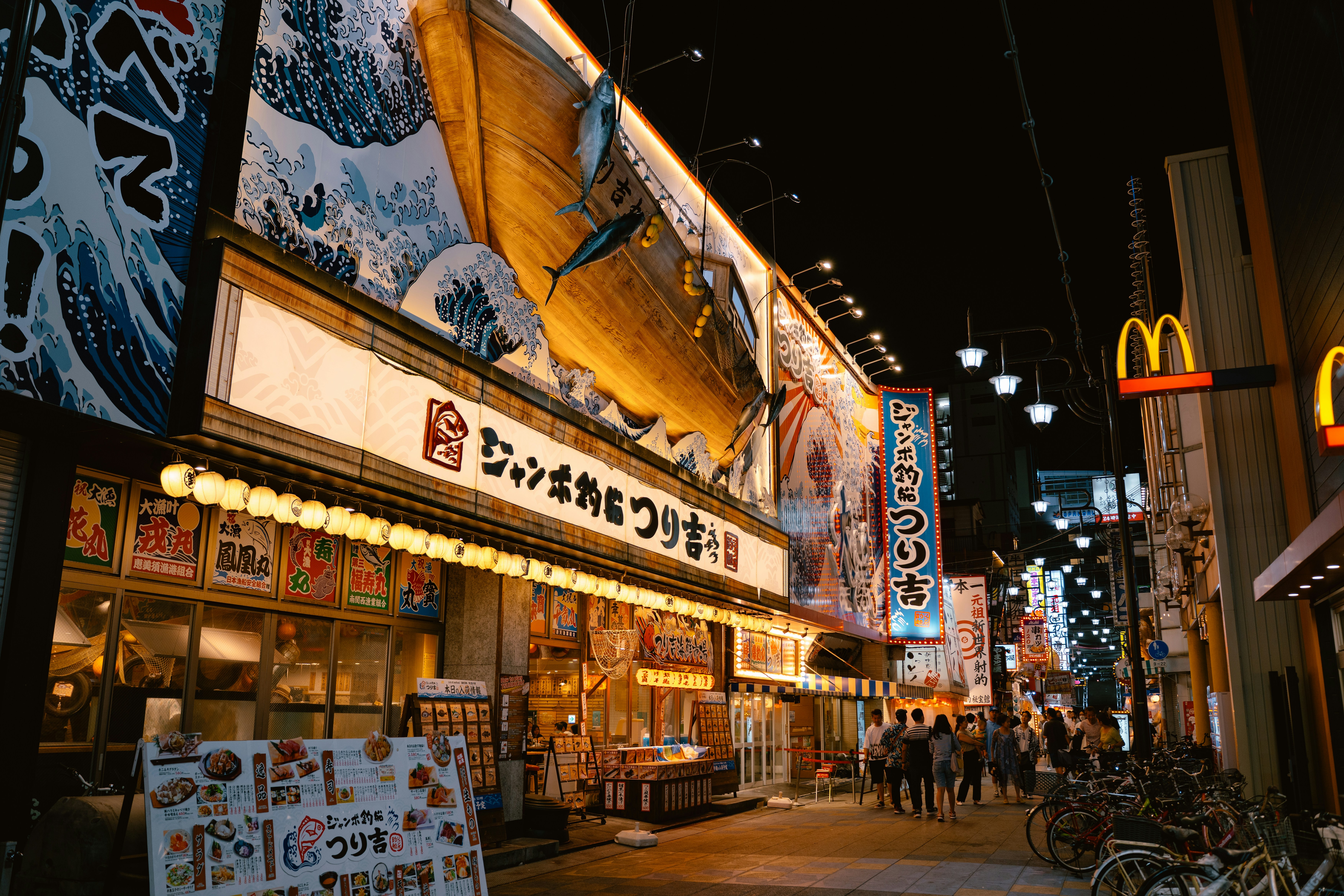 A brightly lit restaurant with a large wooden boat facade at night in Osaka