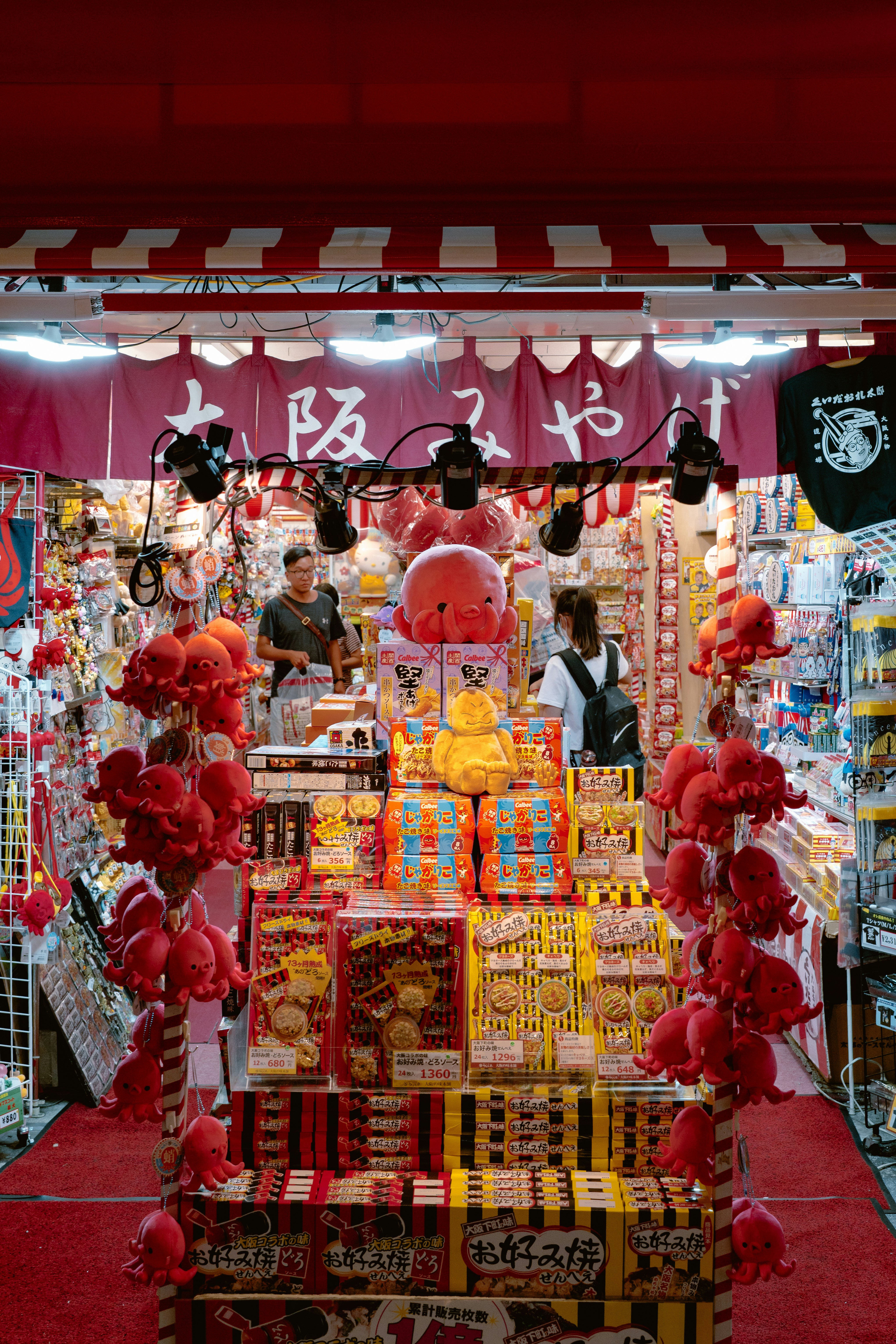 A souvenir shop in Osaka with red octopus plushies and shelves of boxed snacks.