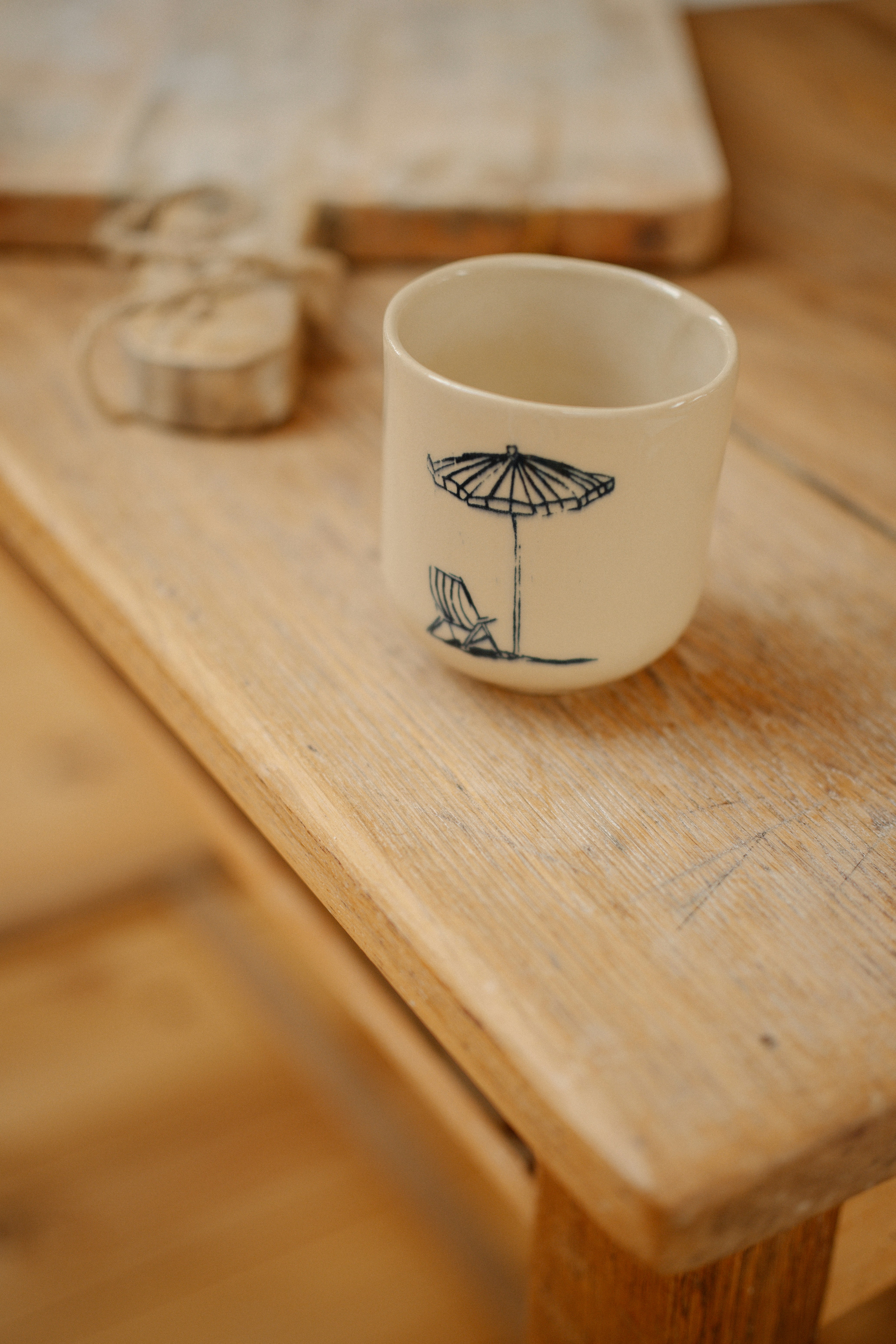 A ceramic cup with a beach umbrella illustration on a wooden table