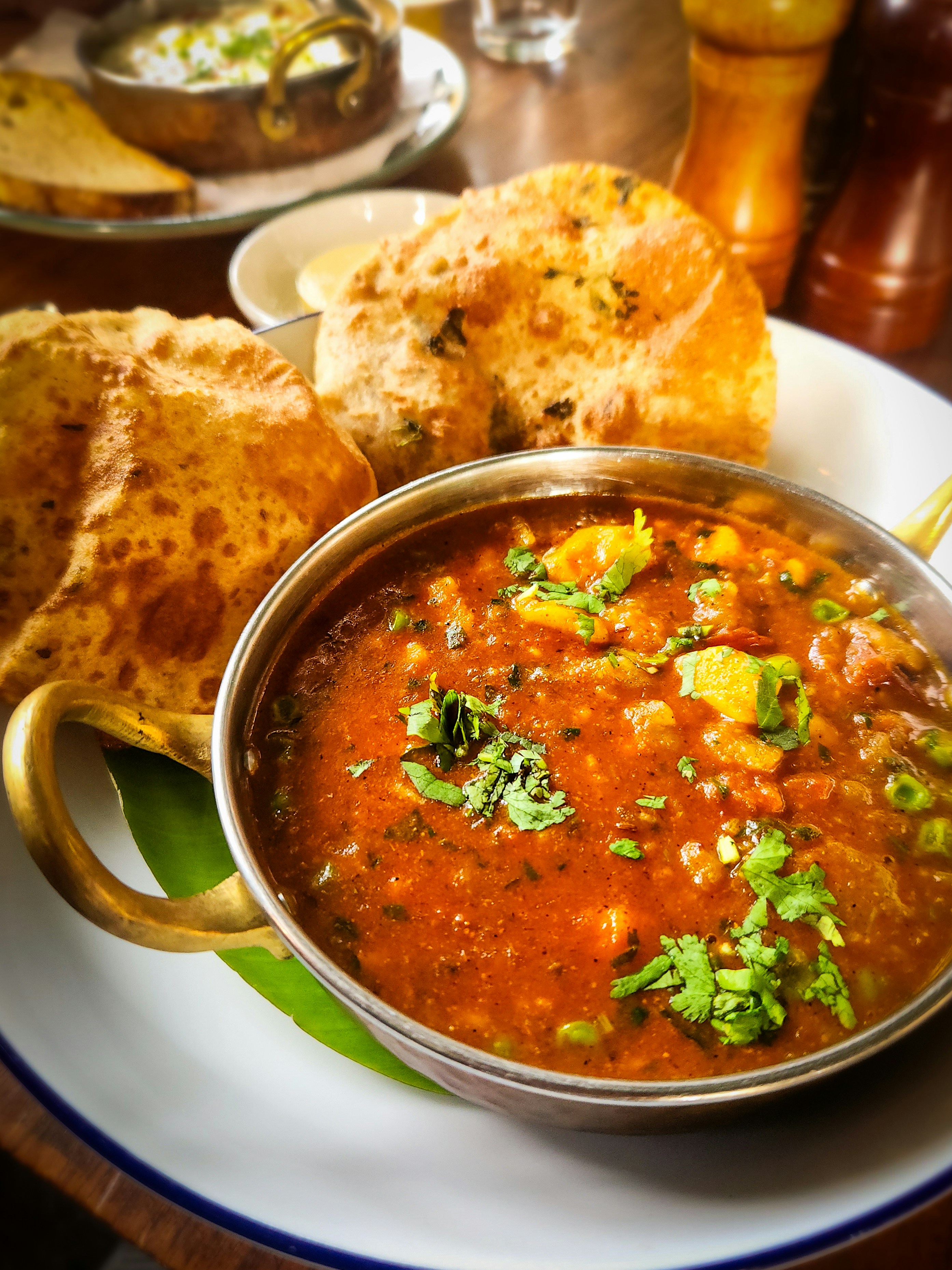 Un bol en métal de curry de légumes épicé avec du pain frit dans une assiette