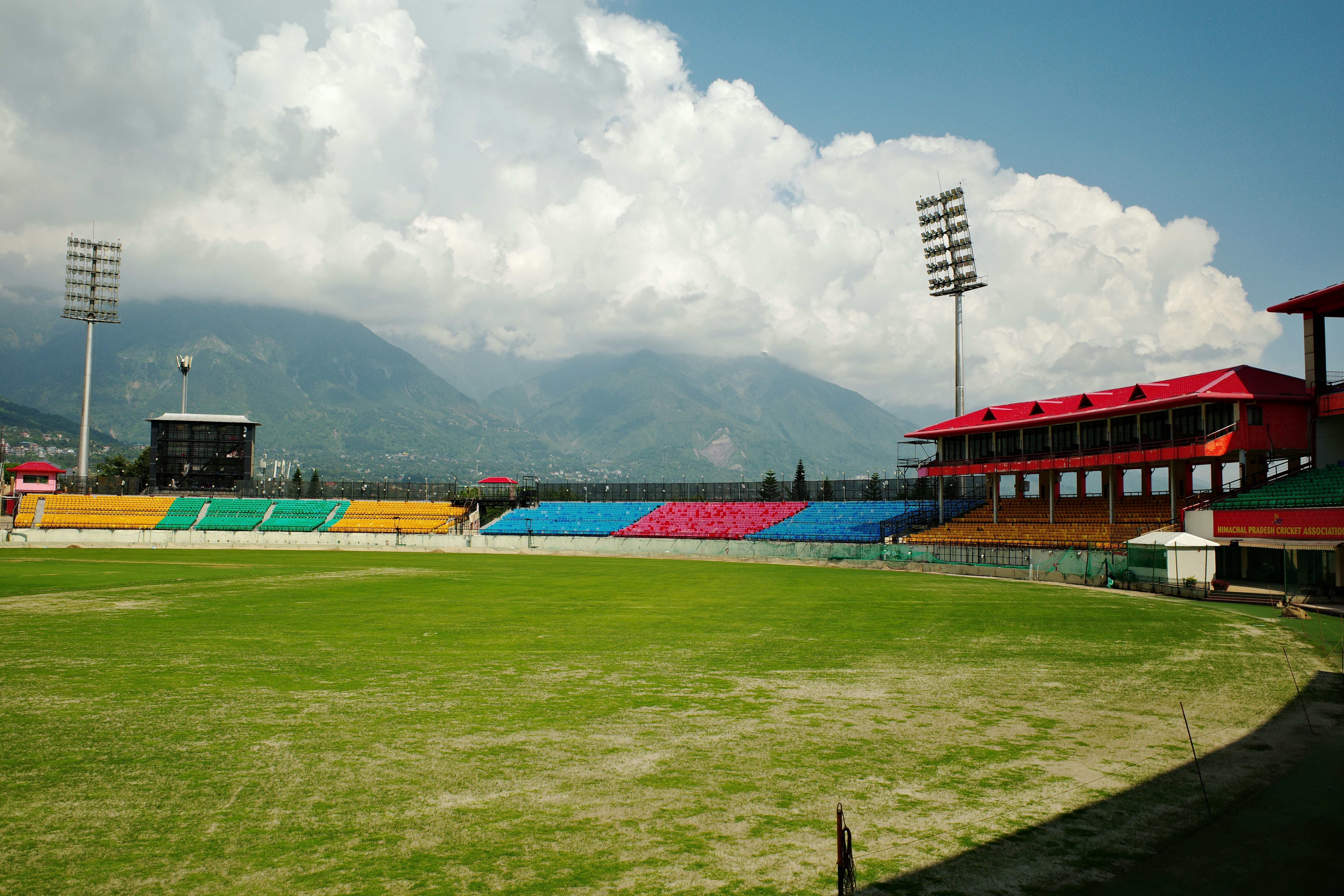 Himachal Pradesh Cricket Association Stadium with colorful seating against a backdrop of mountains