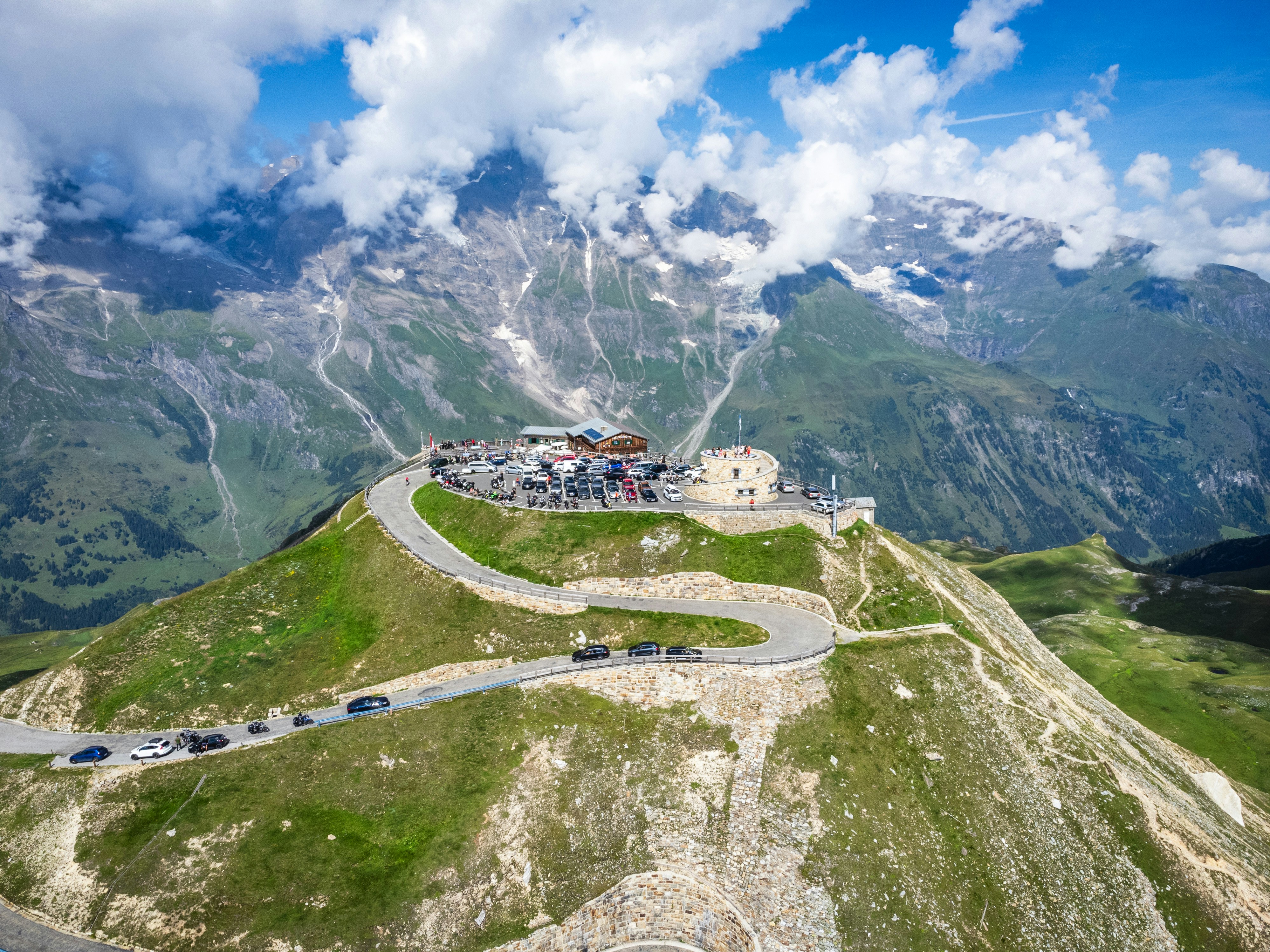 Aerial view of the Edelweissspitze mountain peak with a winding road and parking lot