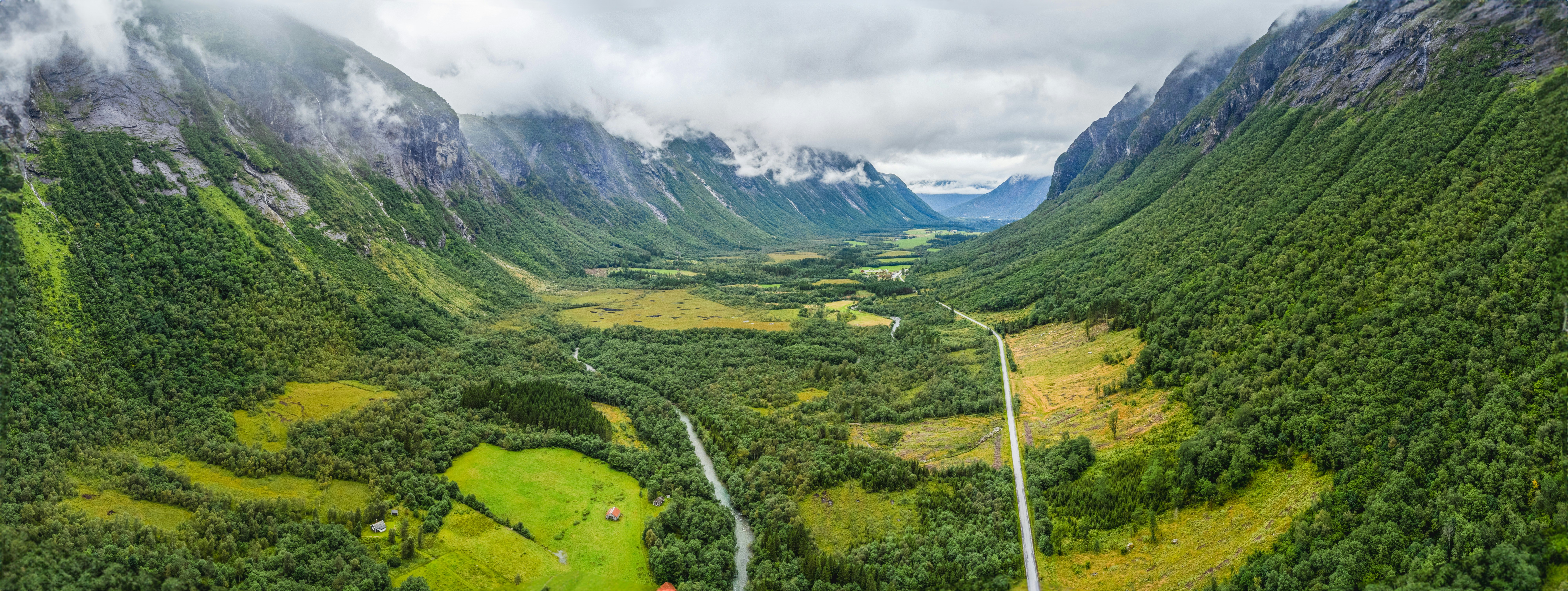 A winding river and road through a lush green valley between steep mountains