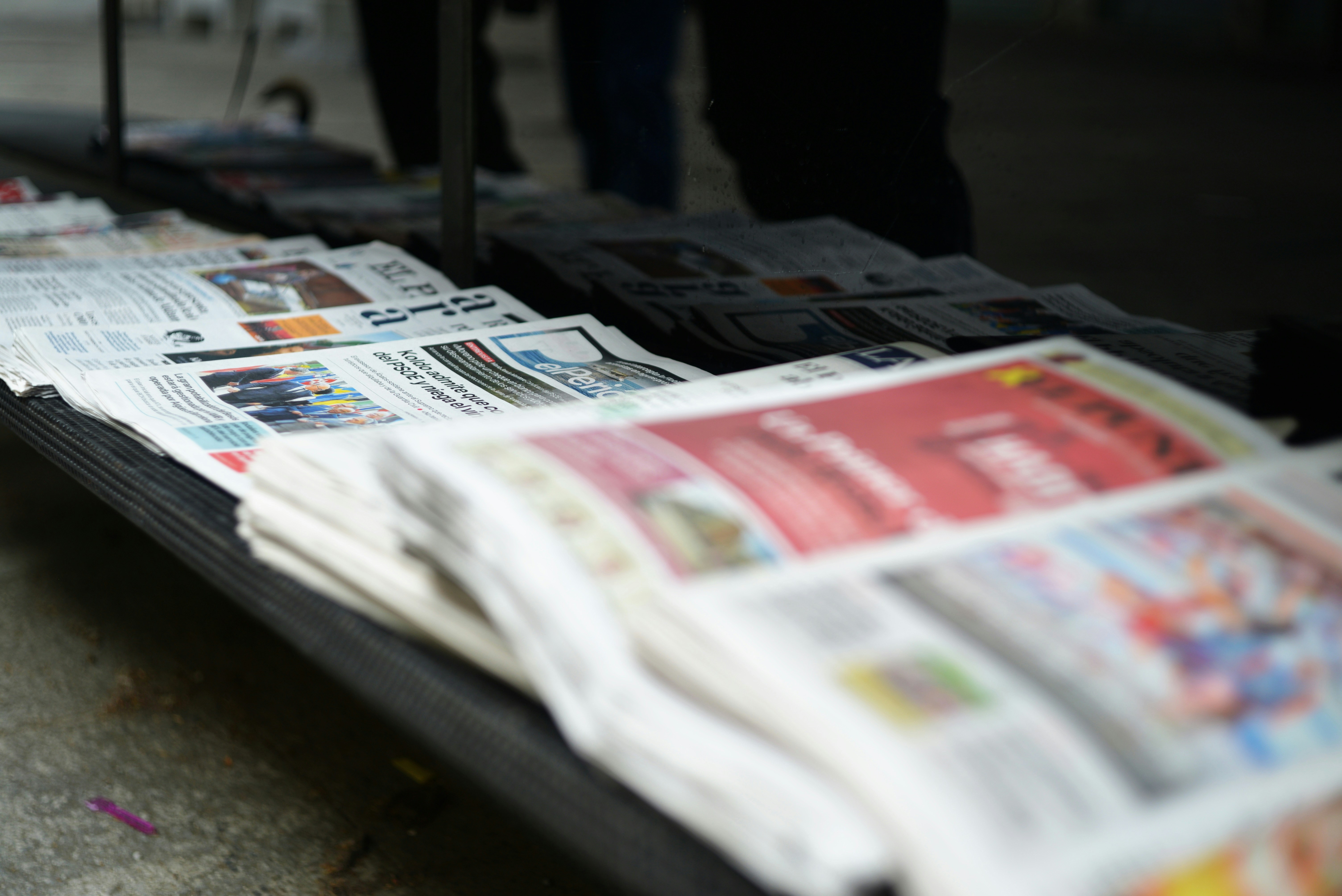 Illustrative stock photo: A stack of newspapers on a metal rack in a public space