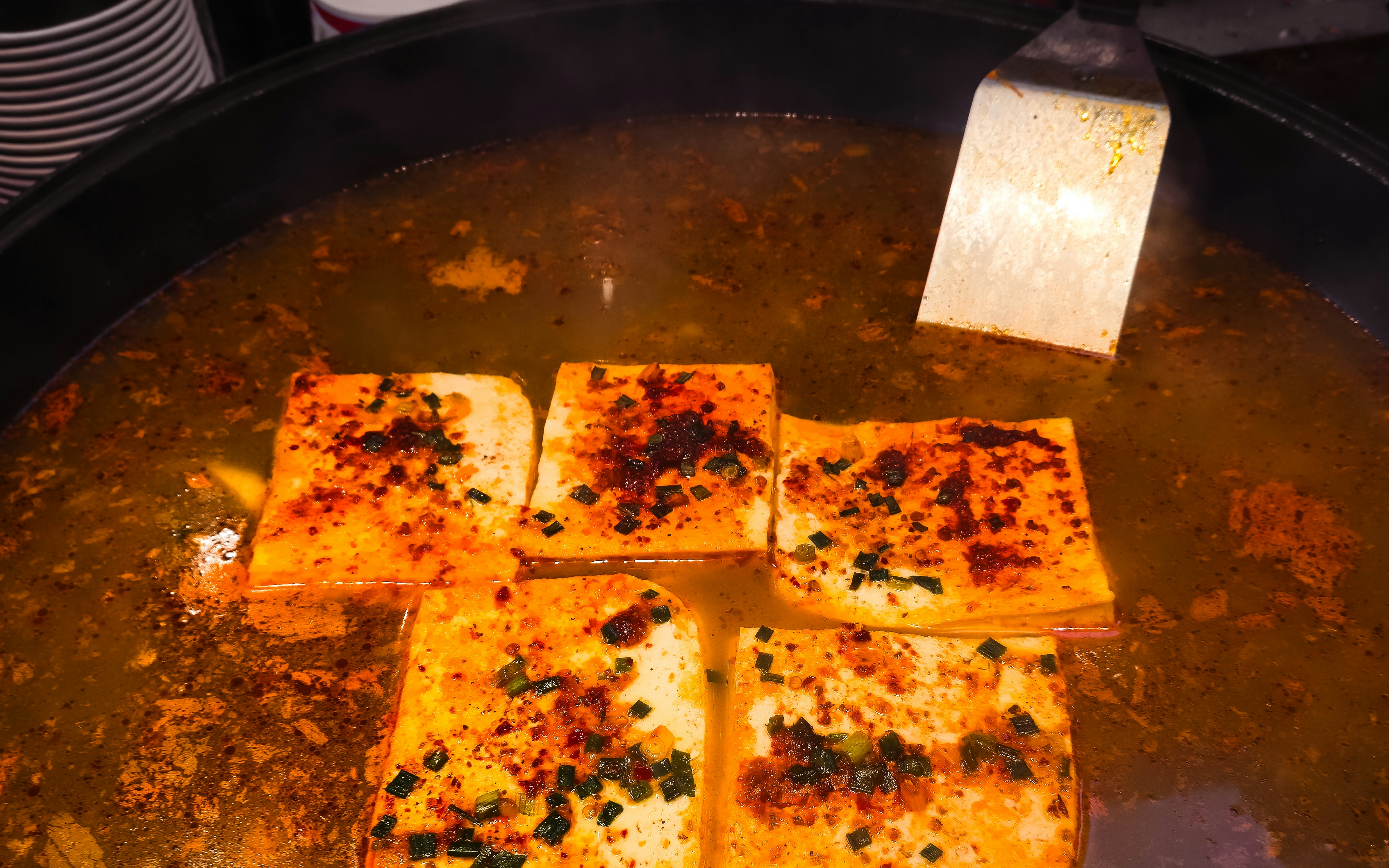 Tofu squares simmering in spicy broth