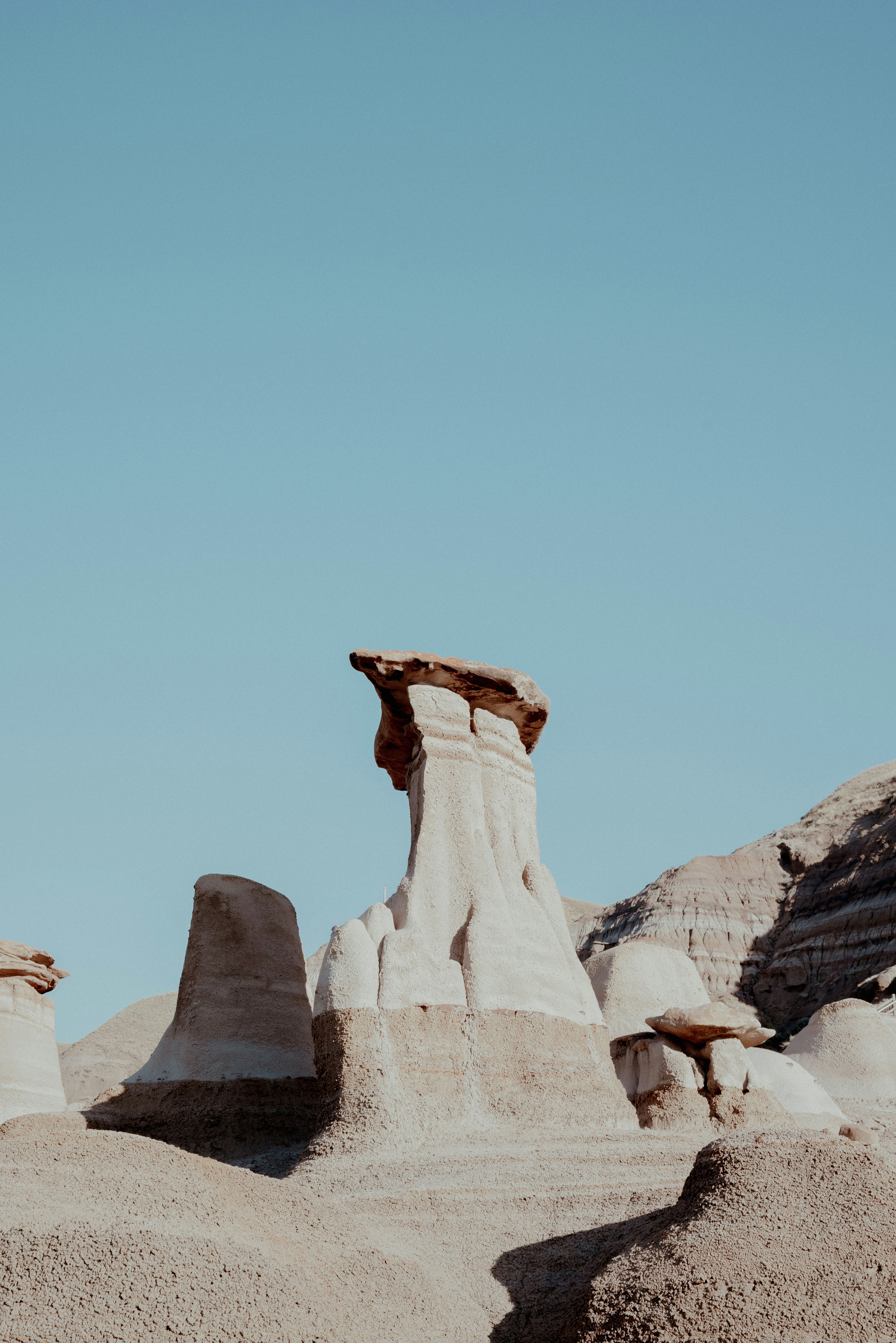 Eroded sandstone hoodoos under a clear blue sky in a desert landscape