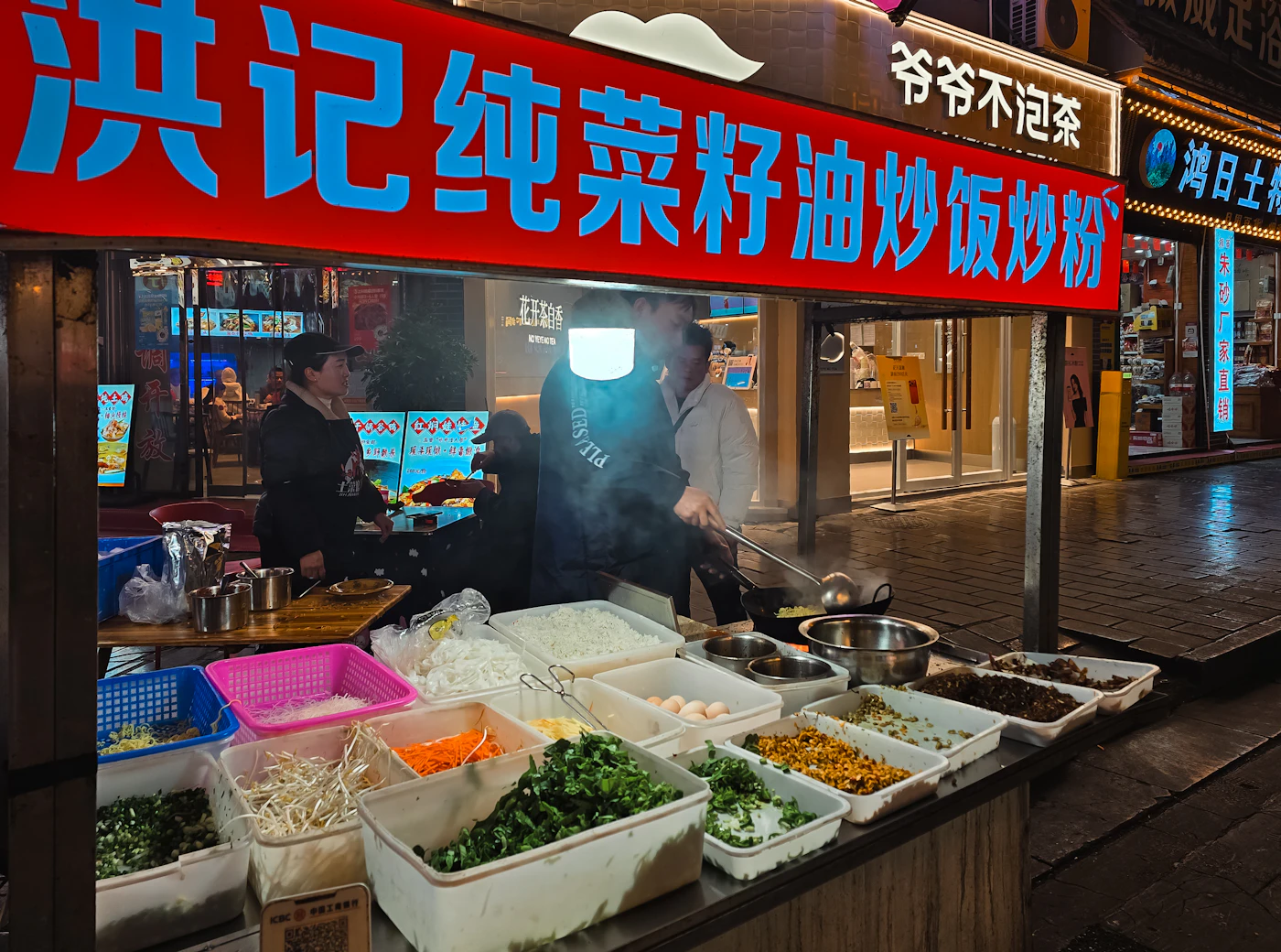 A street food vendor cooking stir-fry in a wok