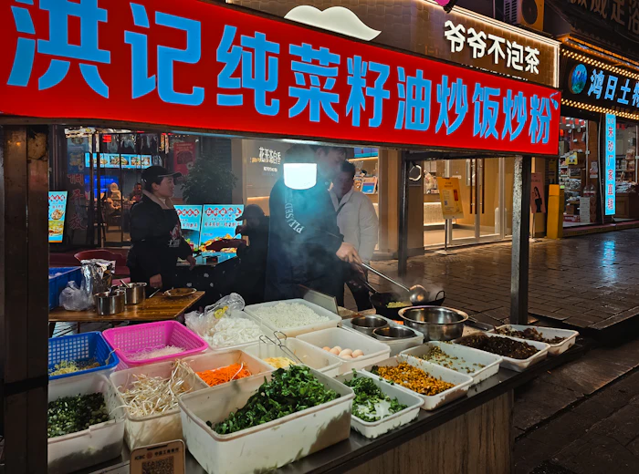A street food vendor cooking stir-fry in a wok