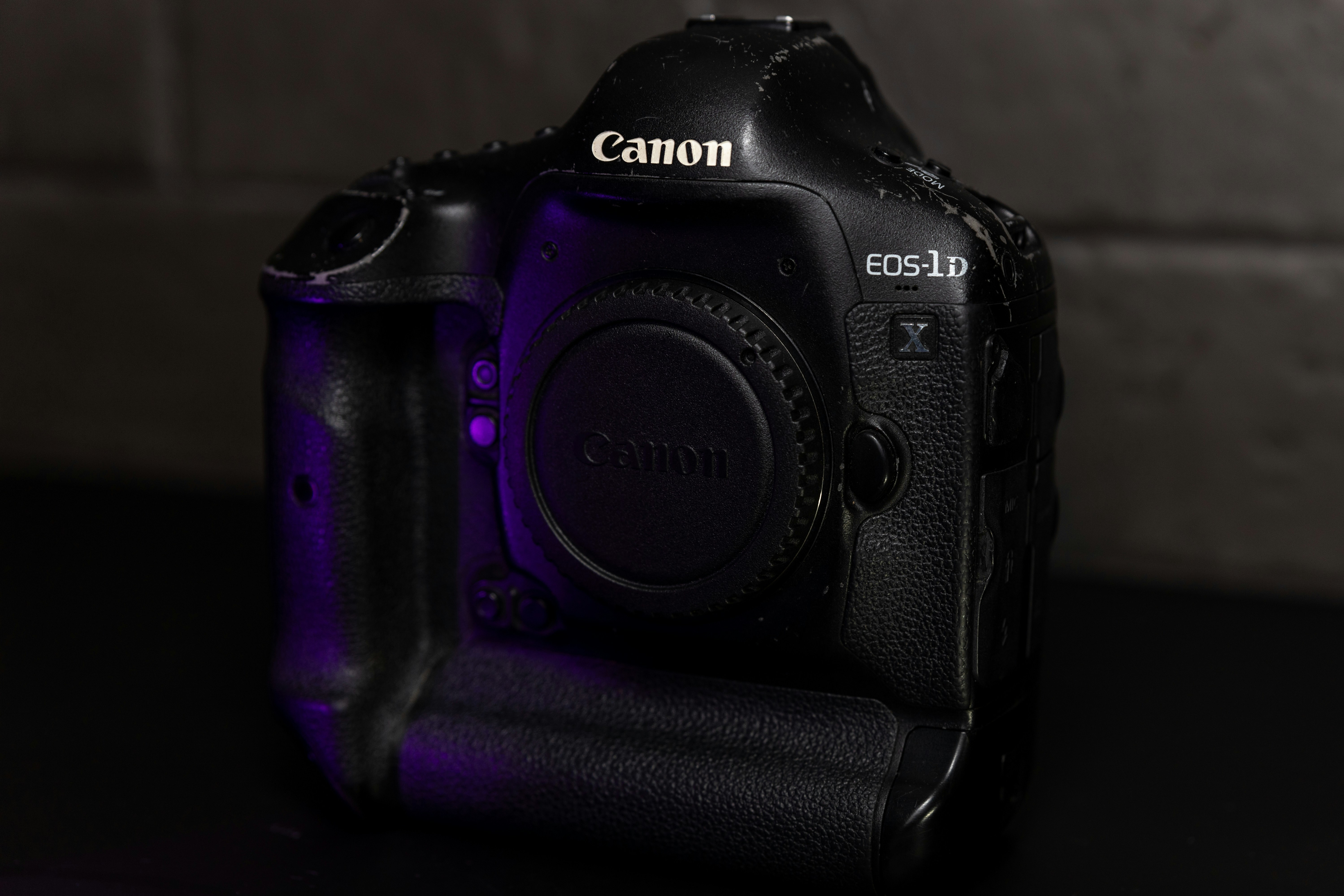 Un cuerpo de cámara Canon EOS-1D X negro con tapa de objetivo en luz morada