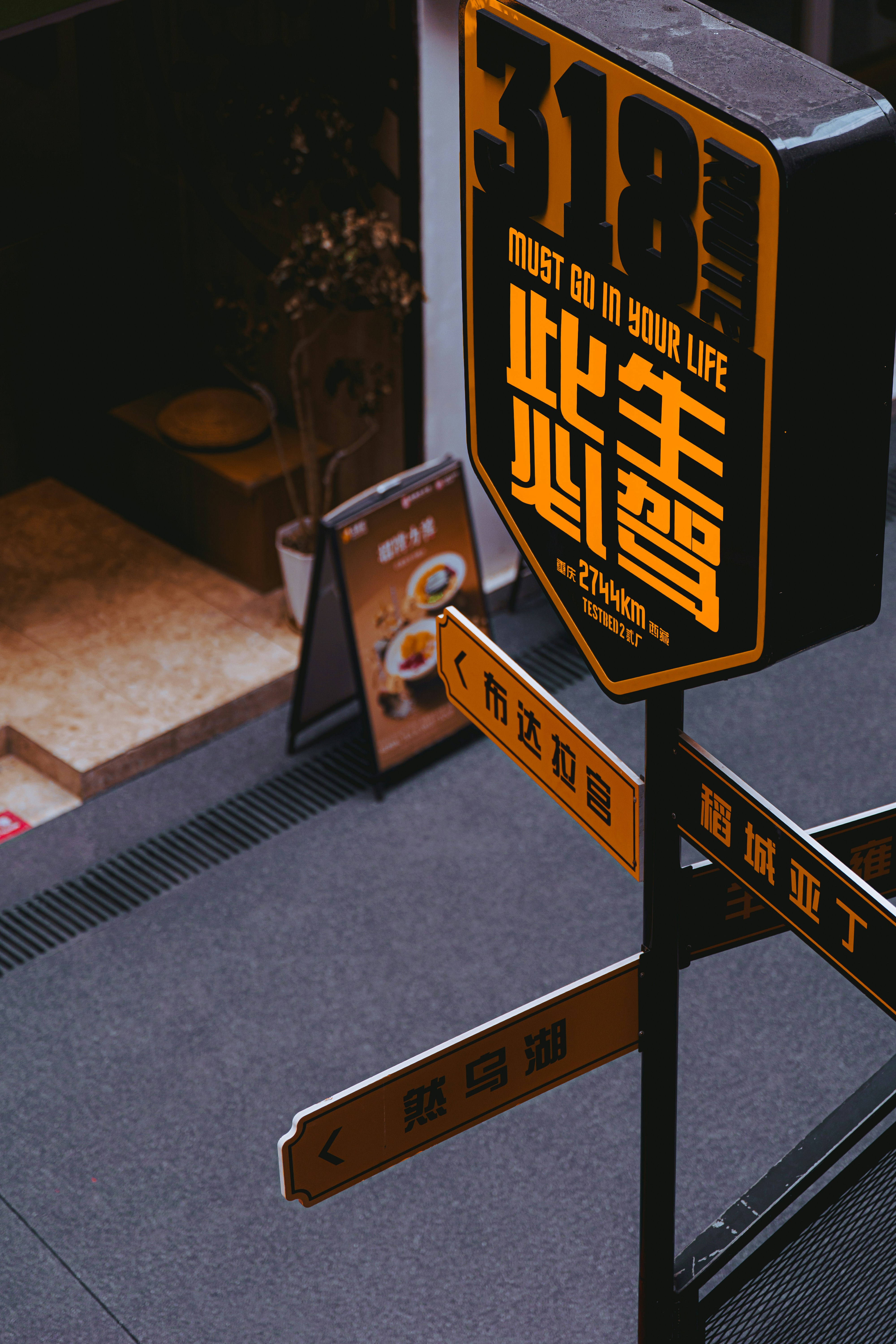 A yellow and black directional signpost with Chinese text on a city street