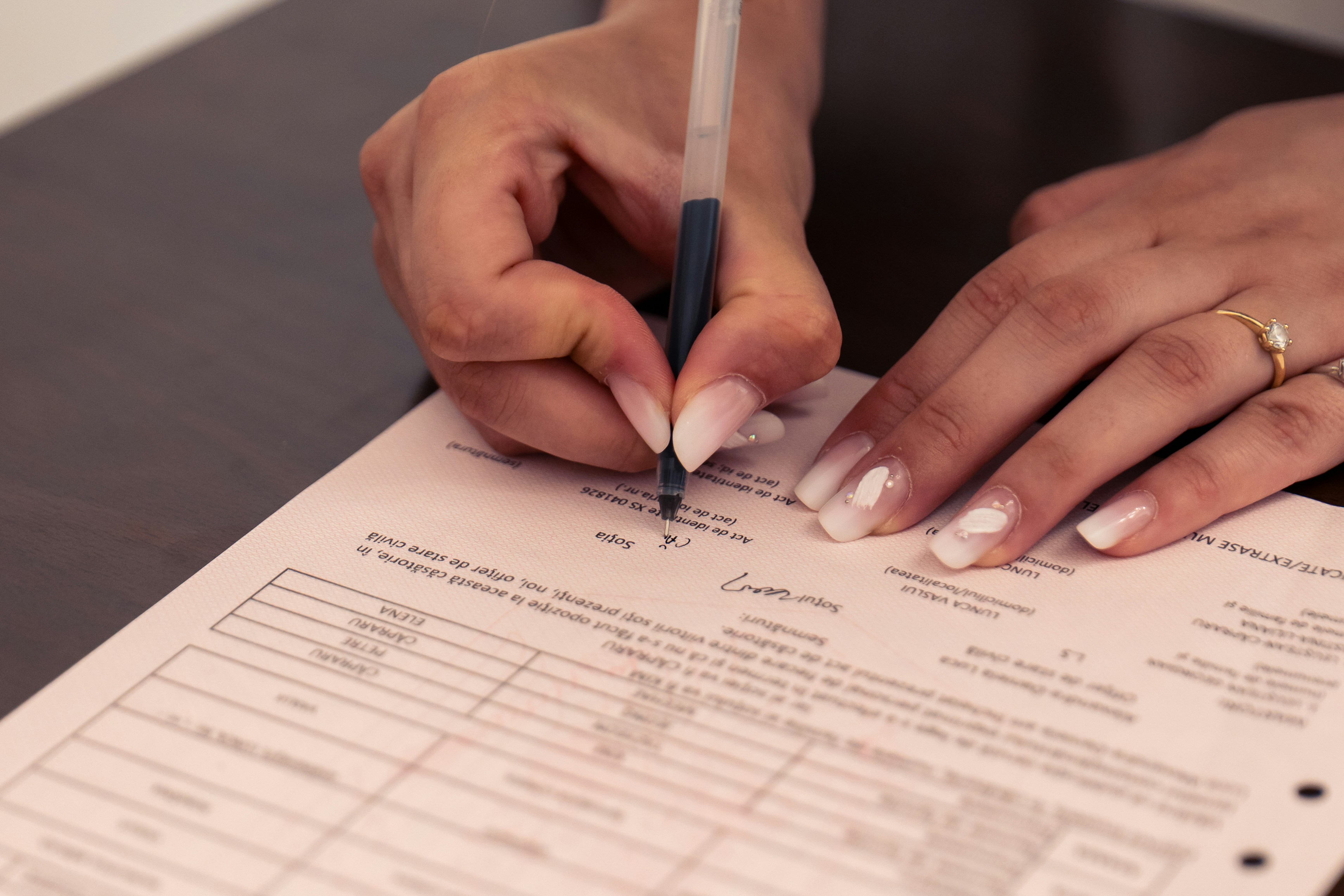 car insurance policy document - A person signing a document with a black pen on a dark table
